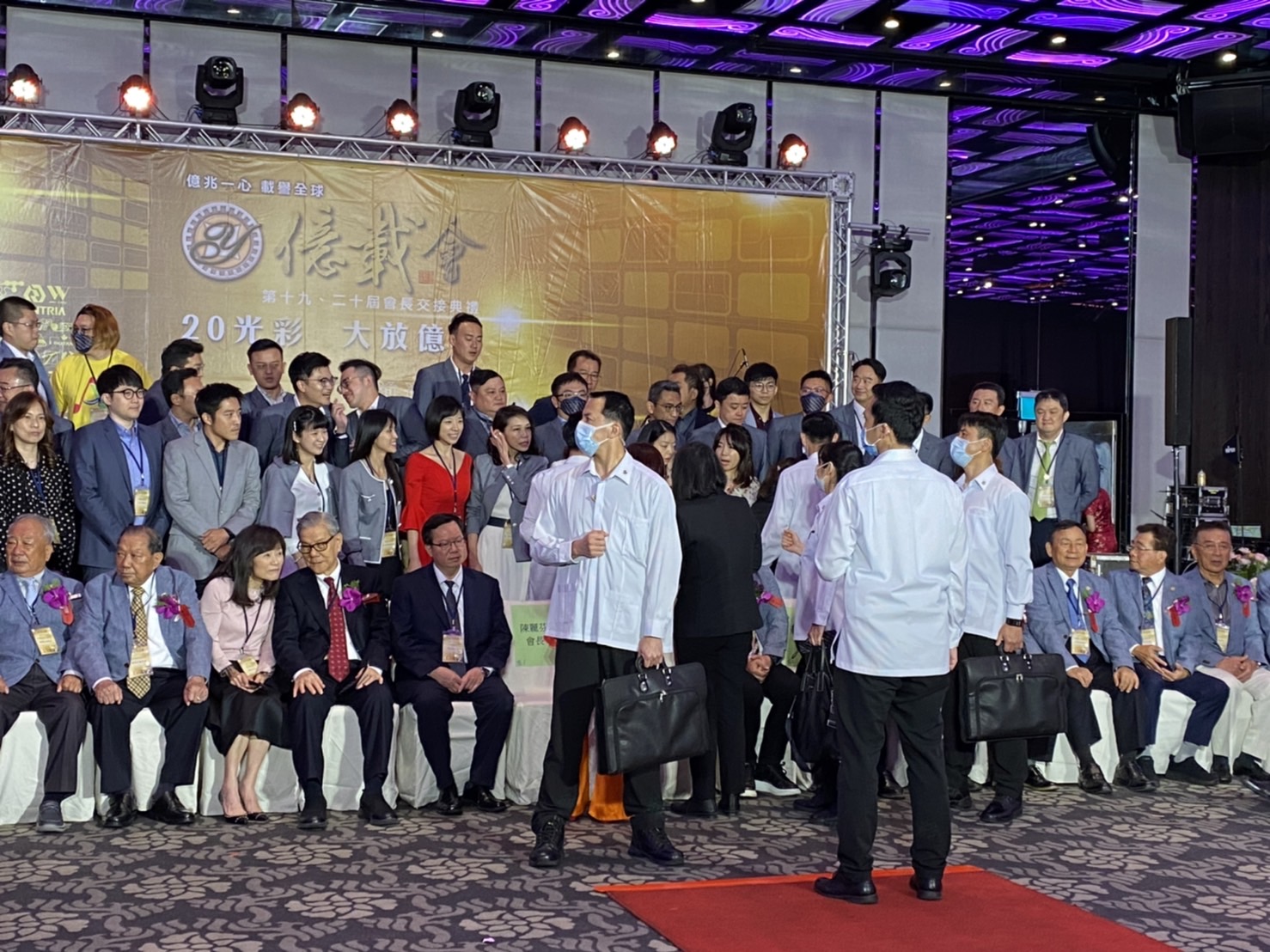 總統蔡英文起身與企業家寒暄，等待拍照就定位空檔，維安小組排成人牆。