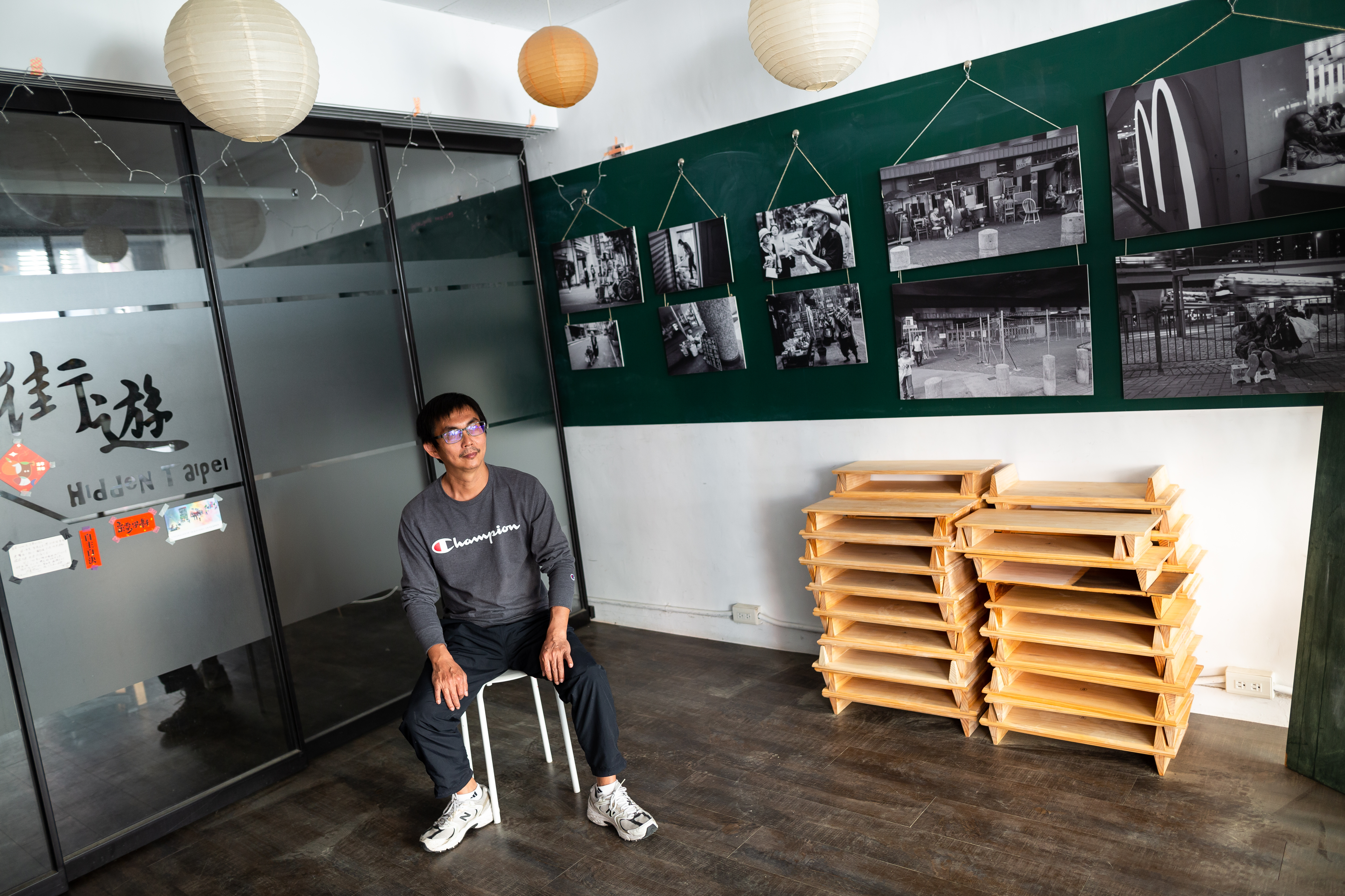 張獻忠在訓練無家者導覽員的「街遊」辦公室，背景是和香港合作的無家者攝影展。