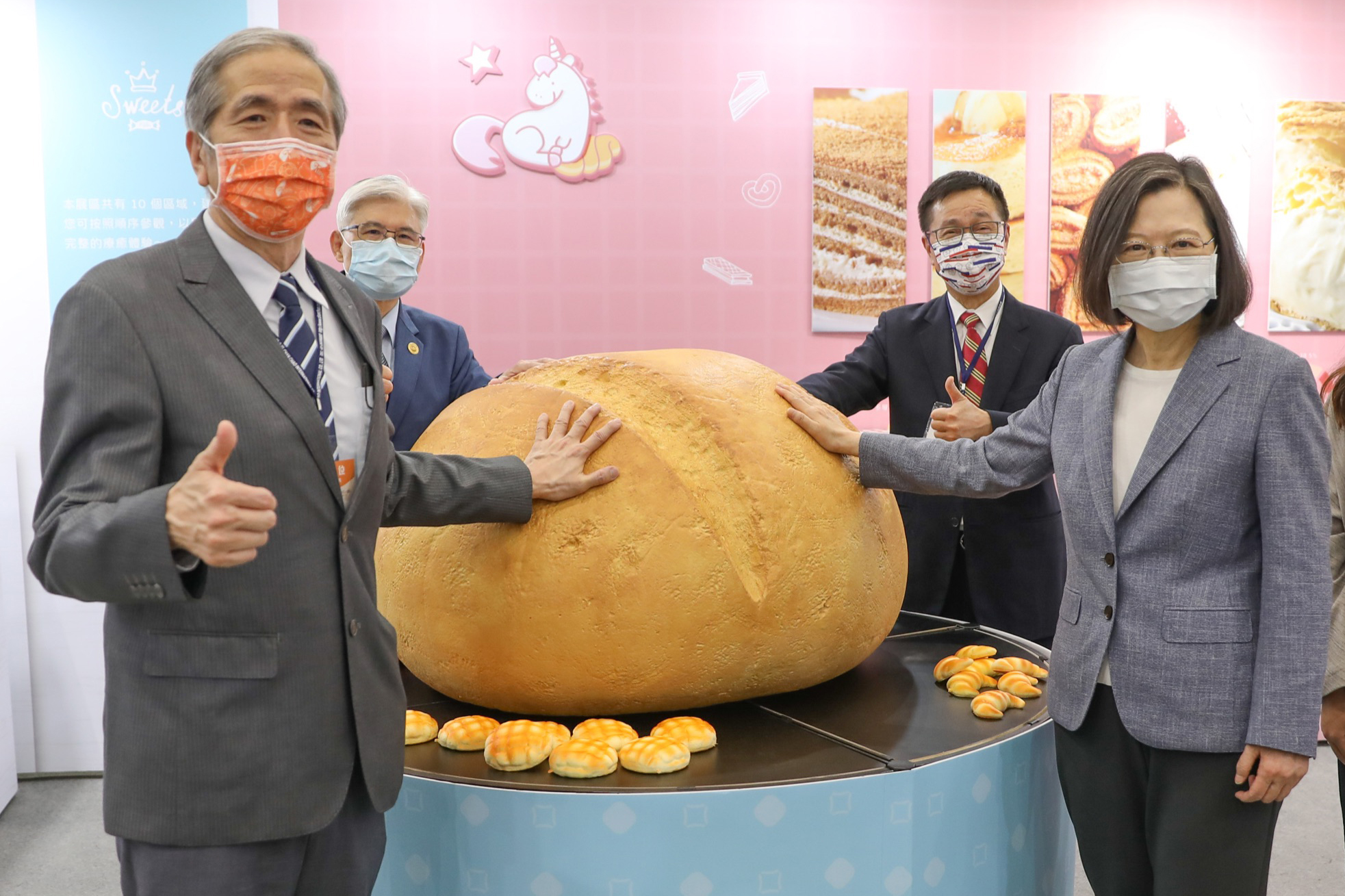 總統蔡英文（前排右）今日出席烘焙展開展記者會，與台北市糕餅商業同業公會理事長周正訓 （前排左）、糕餅全國聯合會理事長周子良（後排左）、總統府國策顧問林見松（後排右）一起在療癒麵包坊感受Q彈巨型麵包。（台北國際烘焙暨設備展提供）