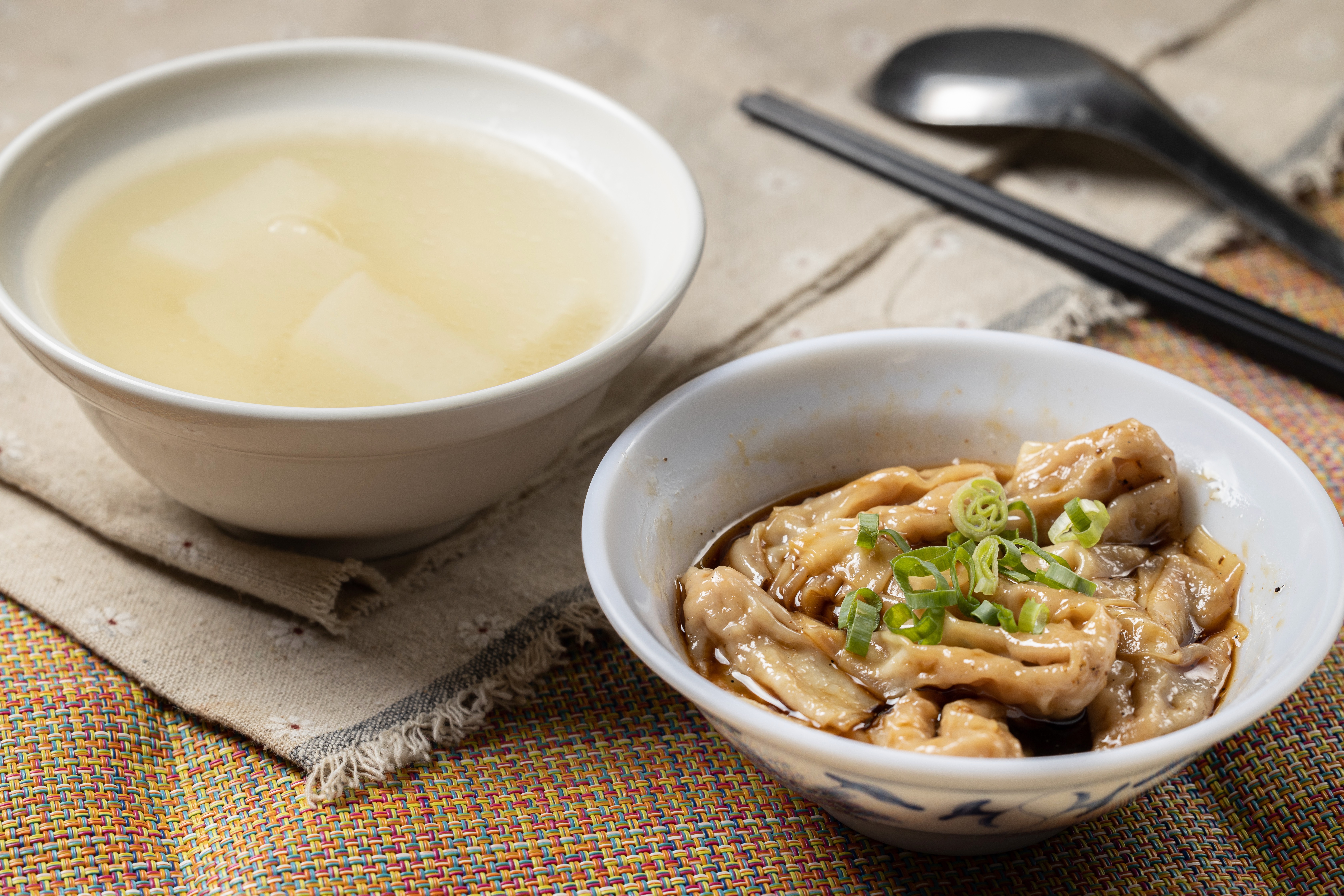 「紅油抄手」（右，70元／碗）也是老闆自製，用豬前腿絞肉製作內餡，散發花椒香氣，搭配一碗以元榆牧場的雞骨熬製，不添加味精及雞粉的「蘿蔔湯」（左，35元／碗），鮮甜純粹。