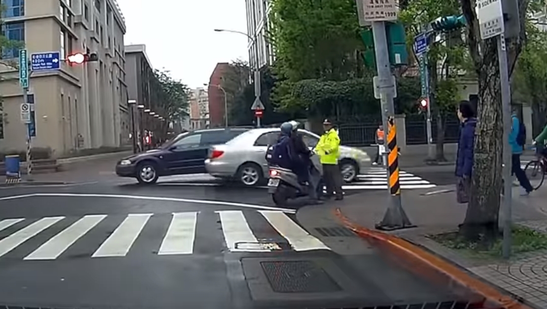 一名家長載孩子，在義交攔阻下，仍違規紅燈右轉。（翻攝自爆廢公社二館臉書）