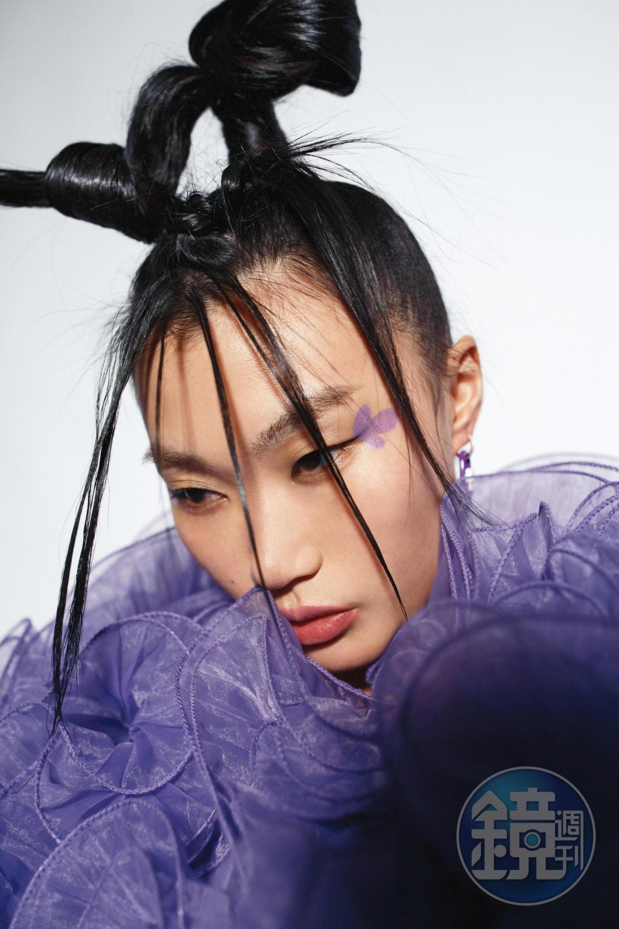 紫色荷葉邊外套NT$9,999 by Iris Apfel X H&M、紫色環扣耳環（單只）NT$4,200 by APM Monaco。