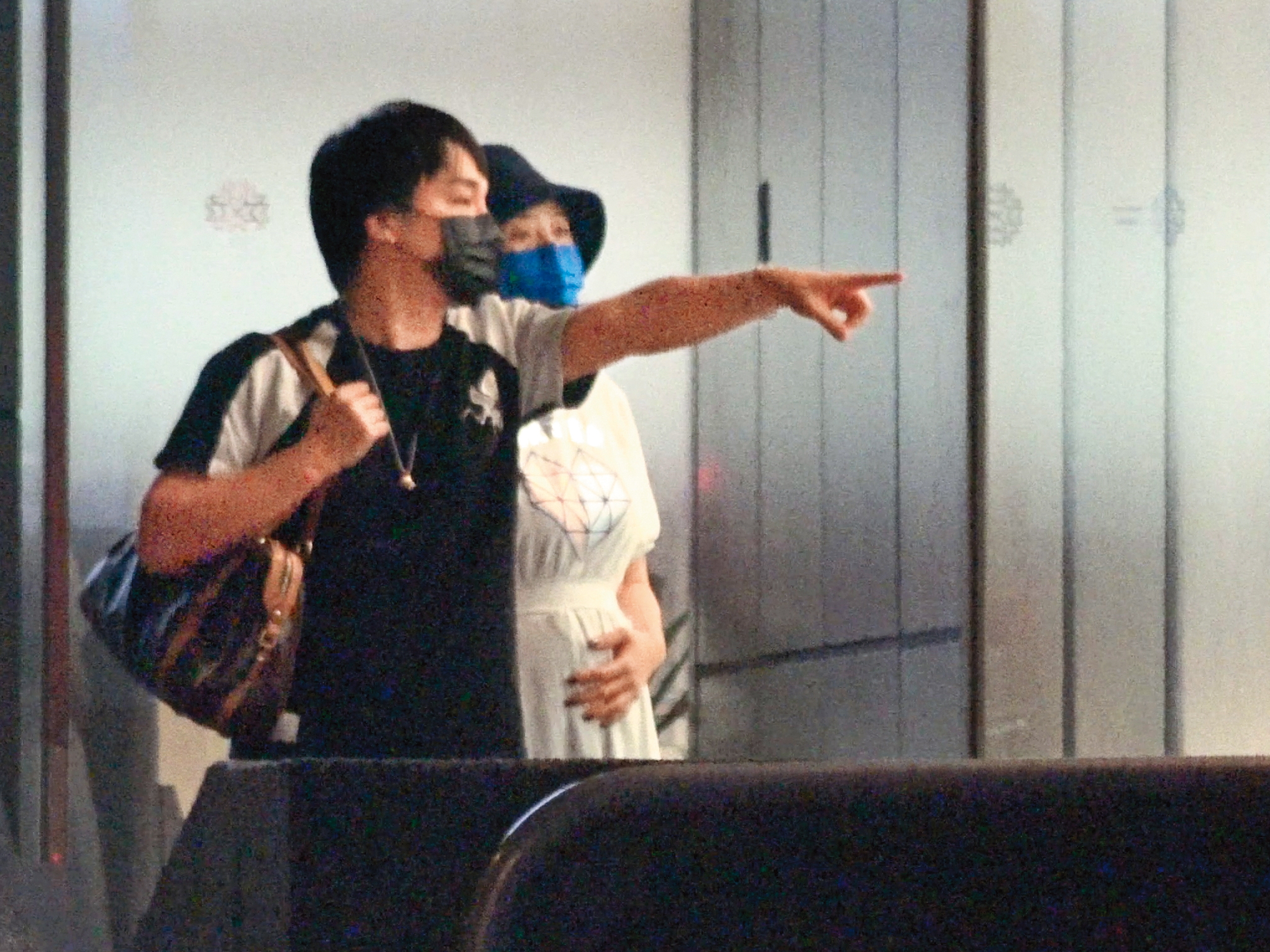 19:32 李亮瑾手撫摸著孕肚，張峰奇負責拿包包，並指向前方。