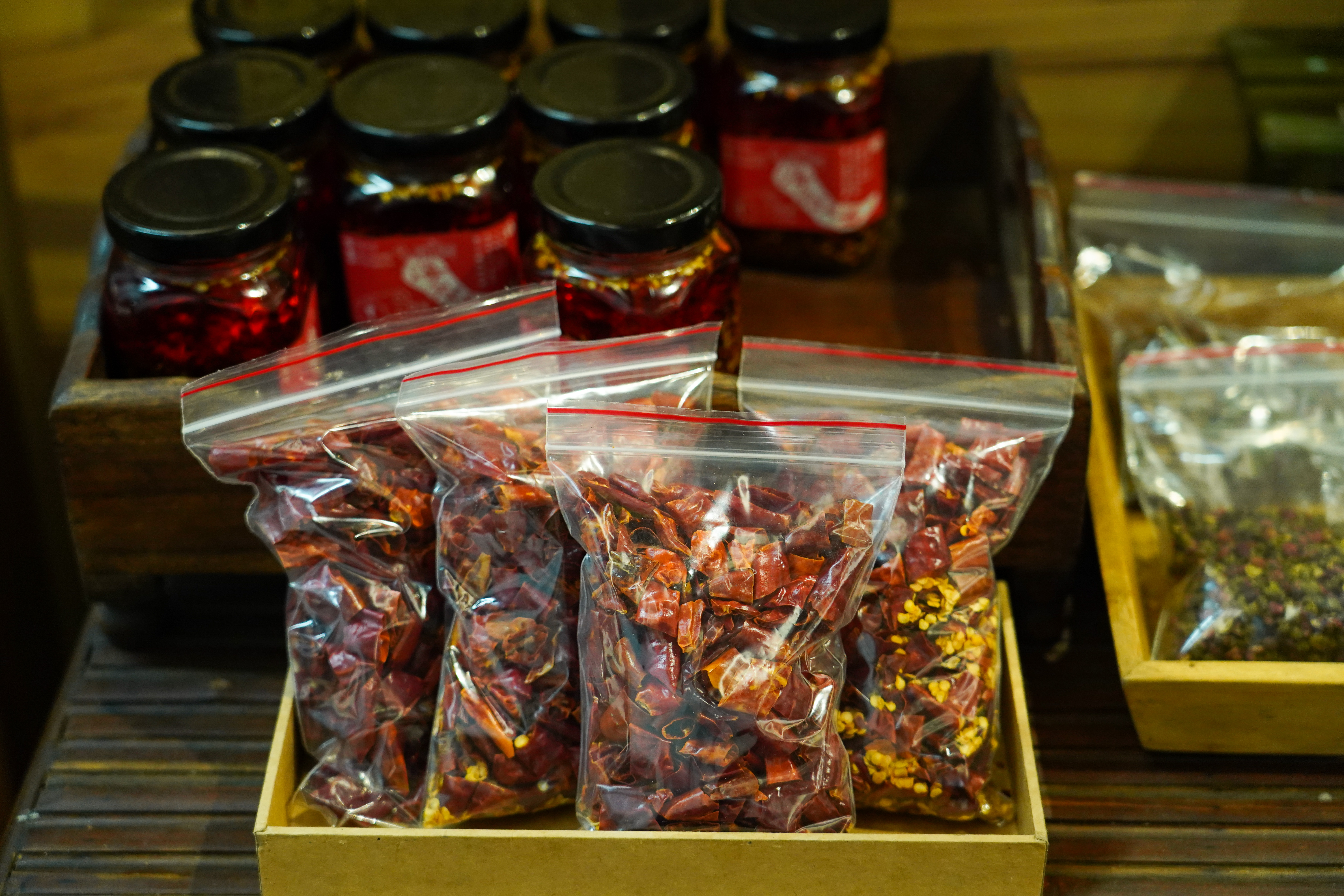 店內吃不過癮，還可把「宮保乾辣椒：二荊條段」（前，50元／包）買回家；道地的「川妹海椒油」（後，200元／罐），海椒為四川人對辣椒的稱呼。