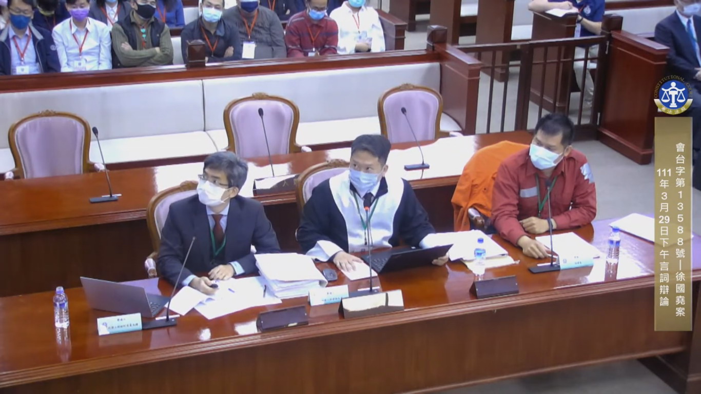 消防員徐國堯（右）由律師邵允亮 （中）及中研院歐美研究所邵允鍾博士（左）擔任代理人出庭爭取復職。（取材自憲法法庭直播網站）