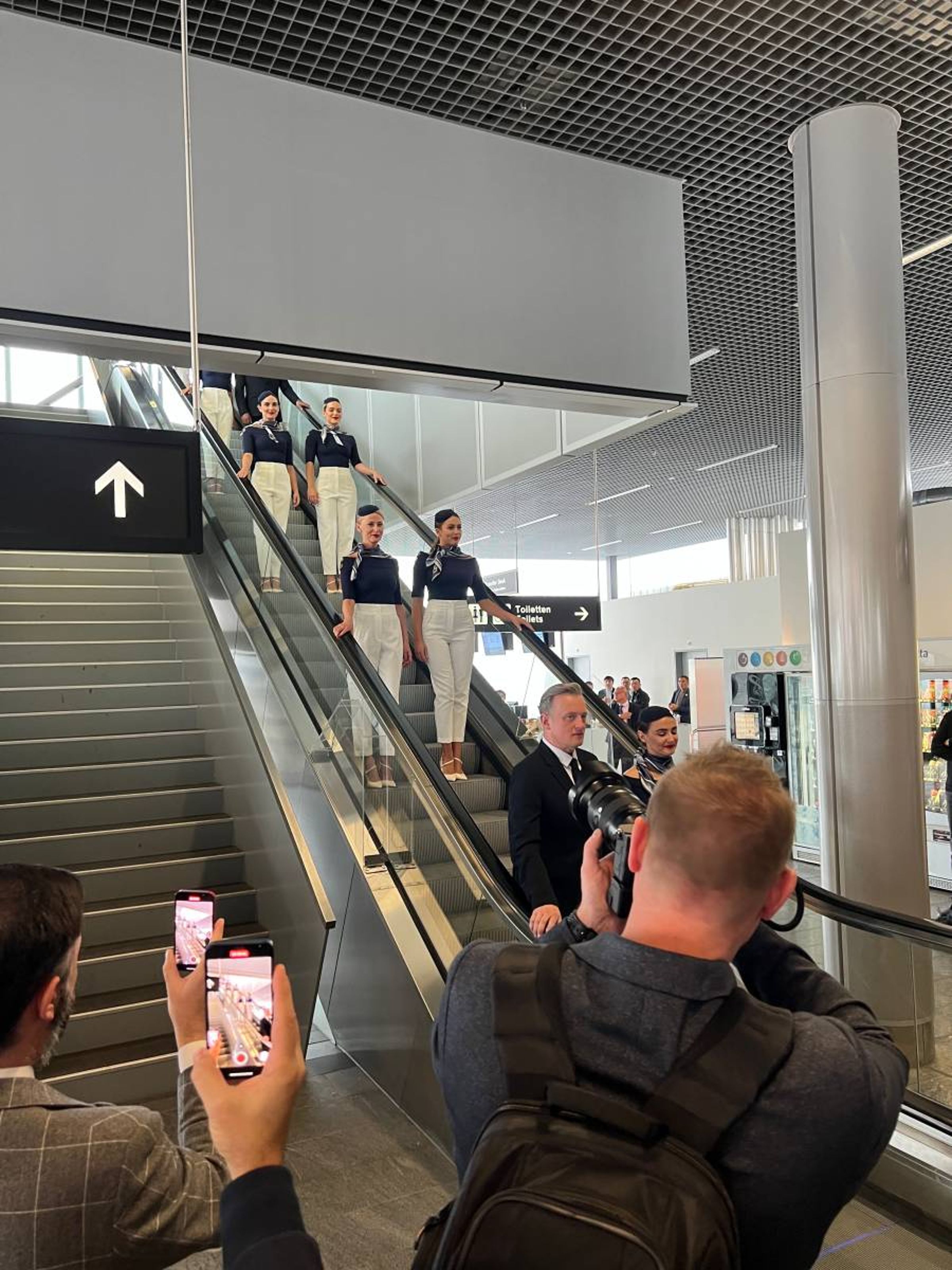 入口處突然一陣騷動，只見二排穿著復古的空姐與空少，順著電梯走了下來。