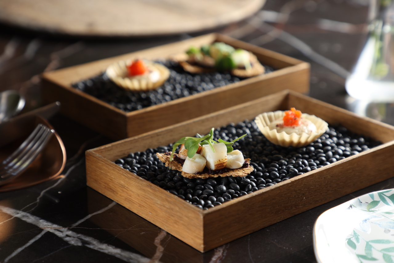 以剩食做成的開胃小點「甜椒．鷹嘴豆．煙燻起司．鯷魚」（右）及「章魚．黑橄欖．亞麻仁籽烤餅」（左），一開場即頌讚綠色飲食理念。（1,580元套餐菜色）