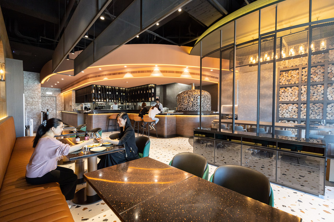 「LA ONE Pizza」的用餐空間，結合大理石、木面及皮革等建材元素，以直弧線條構築出現代感。