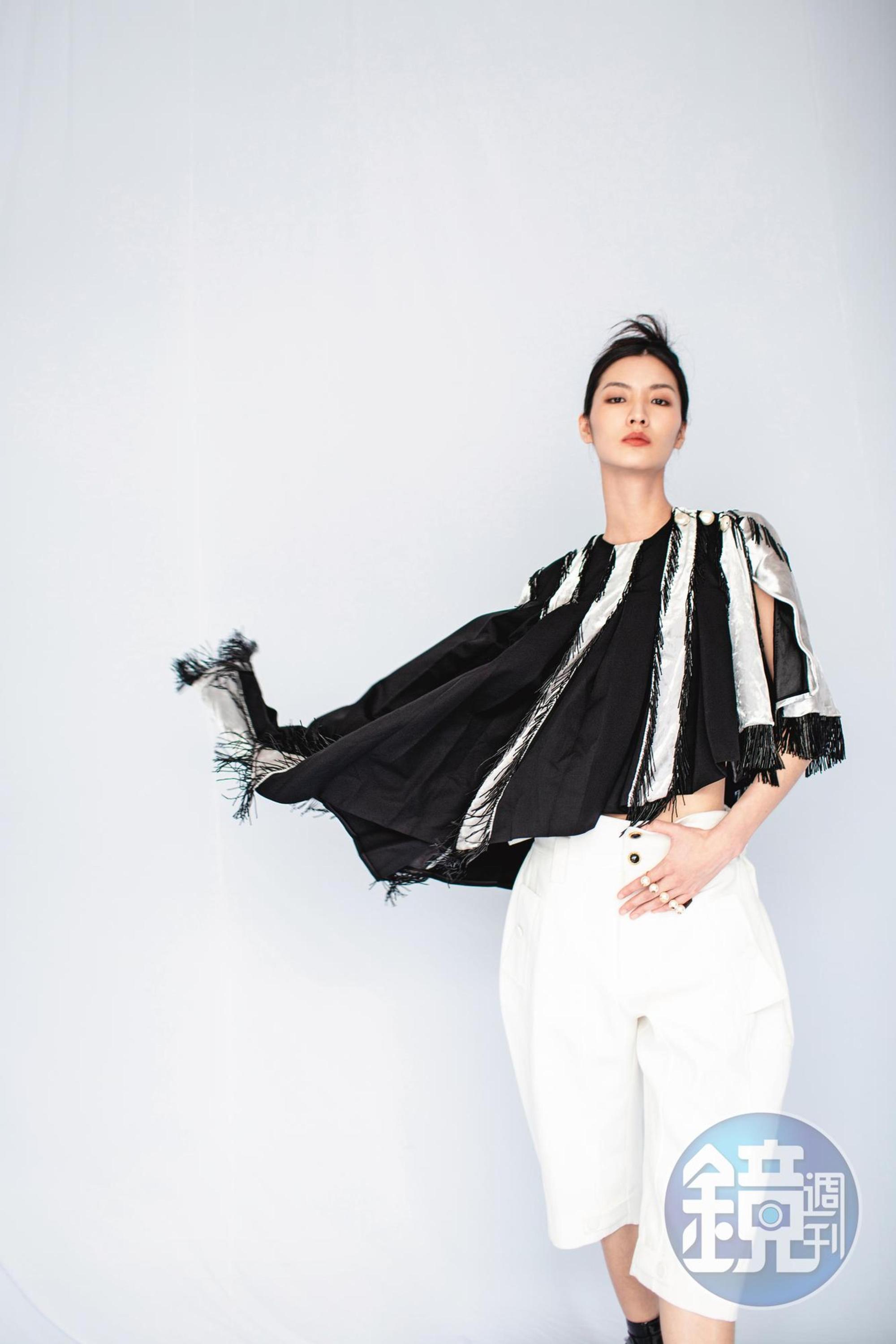 拼接斗篷NT$140,000 by LOUIS VUITTON；短版背心NT$9,700 by LOUIS VUITTON；寬版百慕達褲NT$21,700 by LOUIS VUITTON；珍珠指間戒，價格店洽 by VALENTINO GARAVANI。