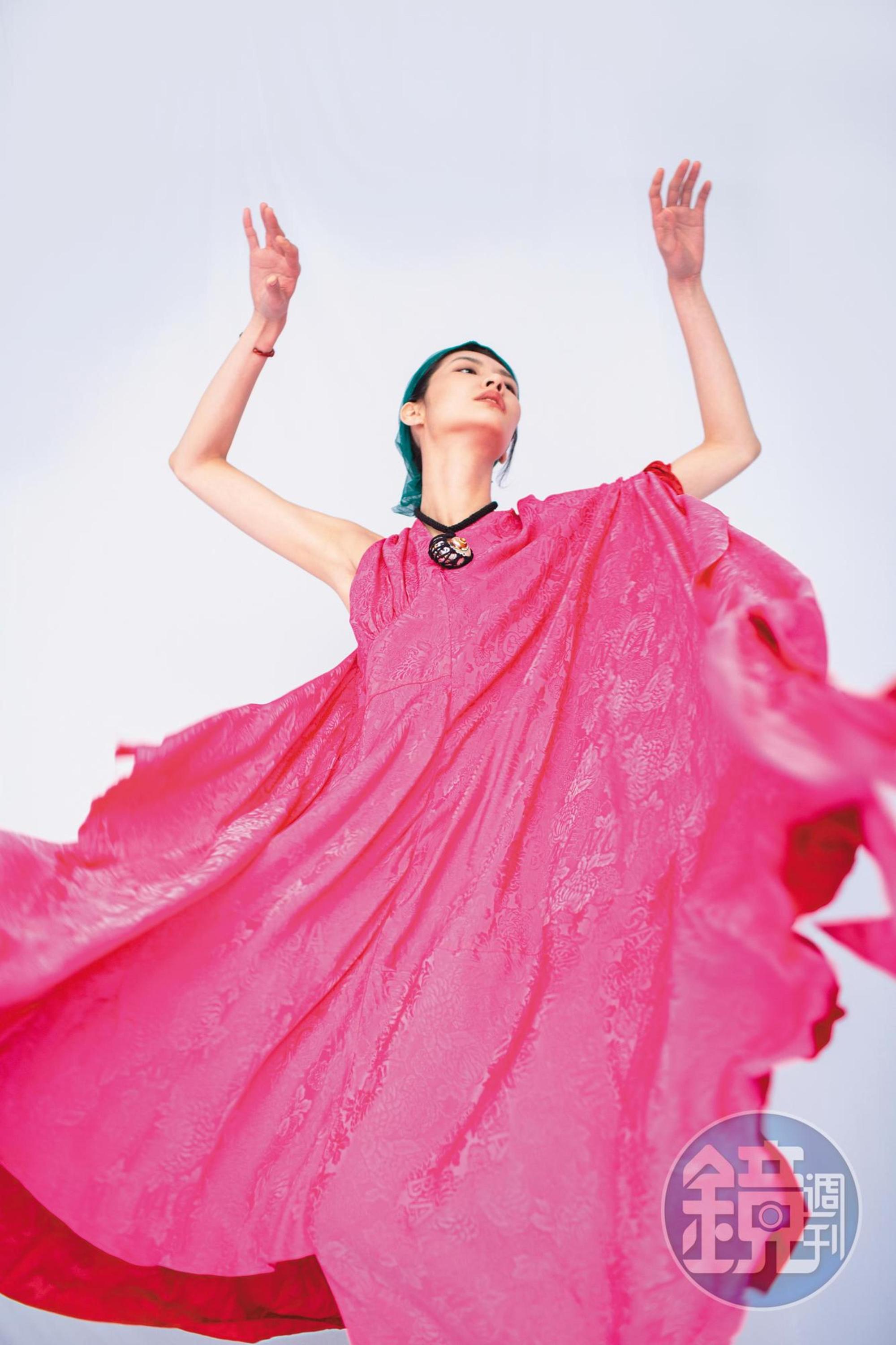 桃紅不對稱造型洋裝NT$141,500 by BALENCIAGA；黑色雙縐絲綢貝殼項鍊NT$25,400 by Chloé；橘紅色納帕紐結造型細手鐲NT$41,000 by LOEWE。