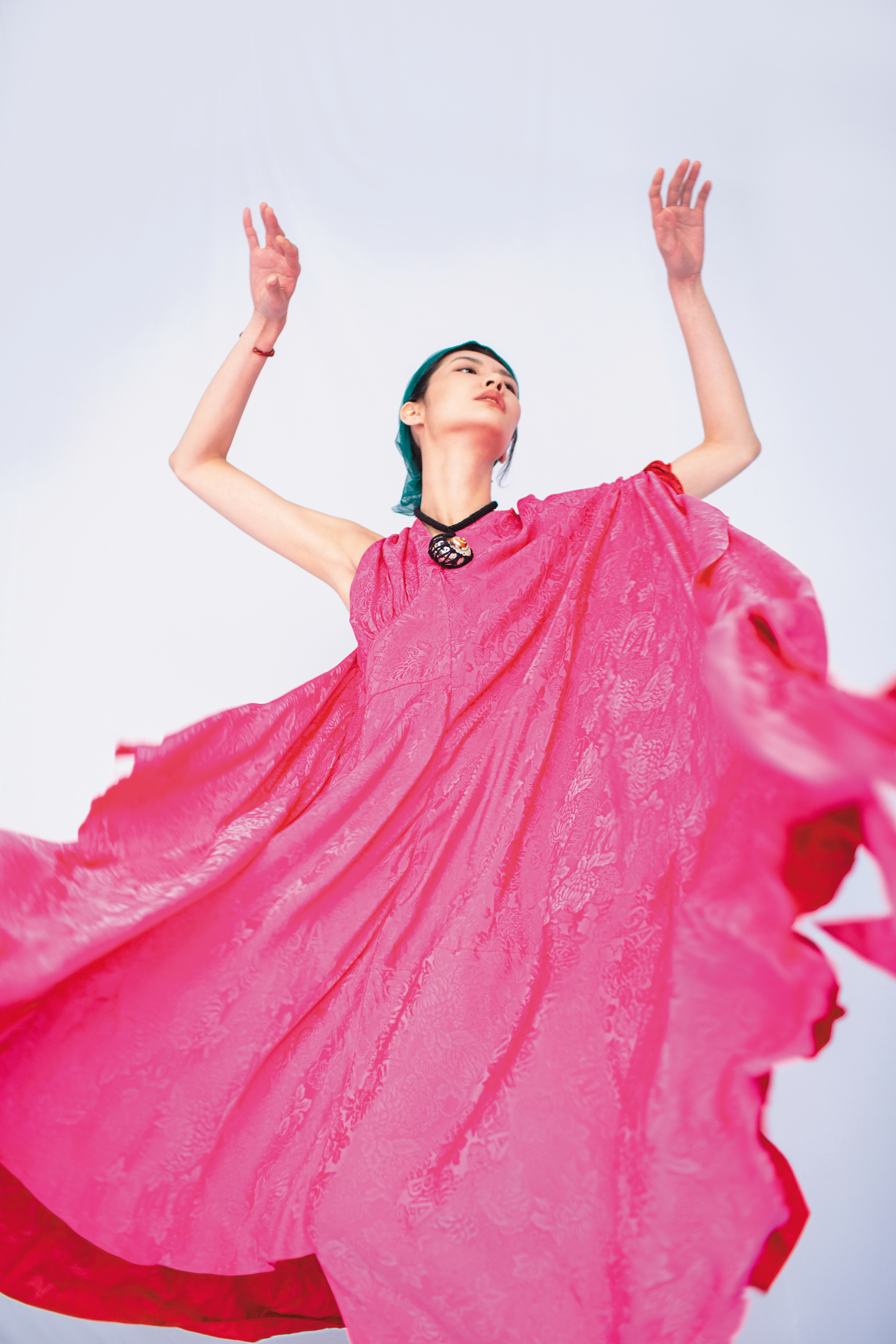 桃紅不對稱造型洋裝NT$141,500 by BALENCIAGA；黑色雙縐絲綢貝殼項鍊NT$25,400 by Chloé；橘紅色納帕紐結造型細手鐲NT$41,000 by LOEWE。