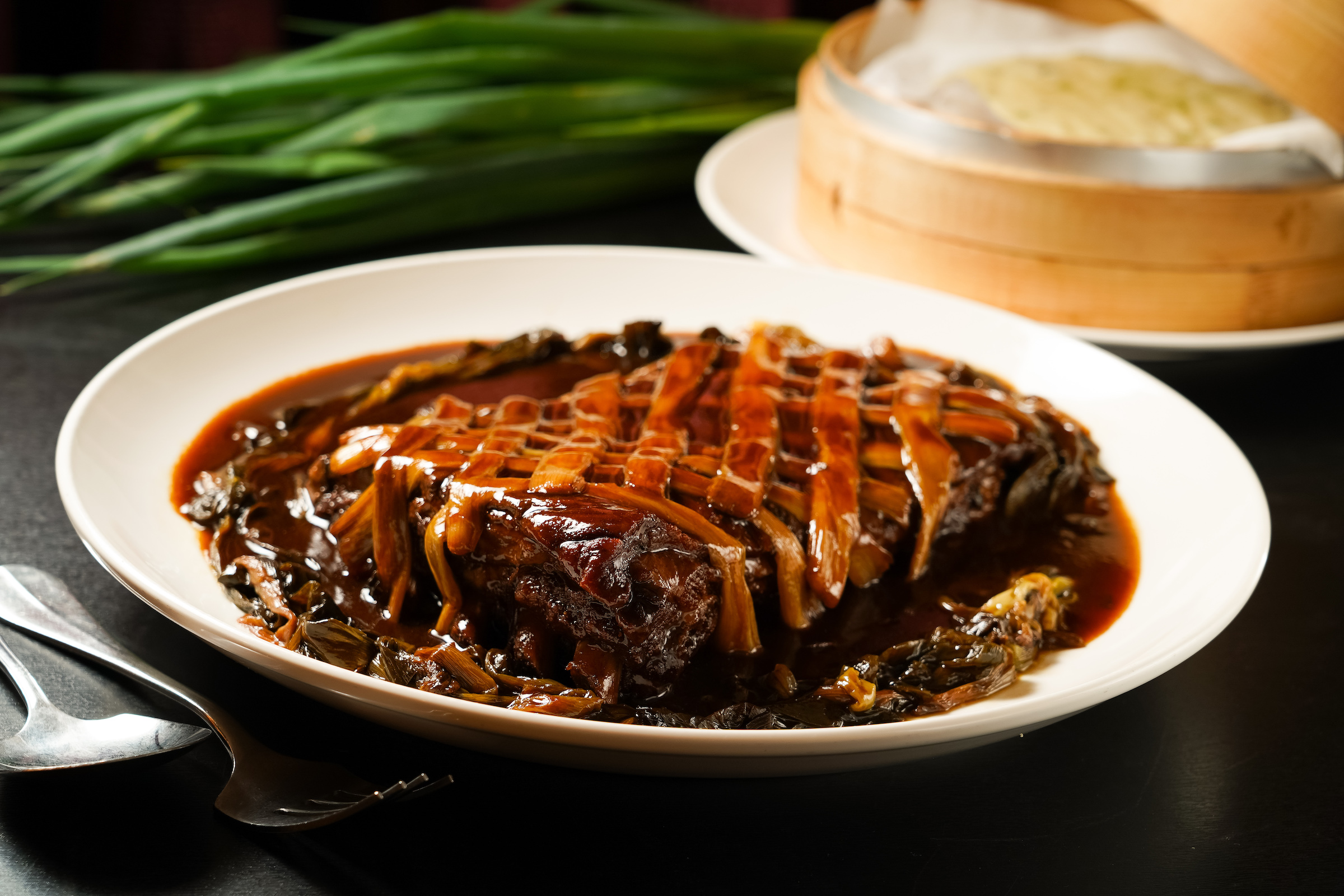 「金蔥燜玉排」用蔥㸆手法長時間燜滷，肉質酥爛，滿溢三星蔥的甜香。（2,000元／份）
