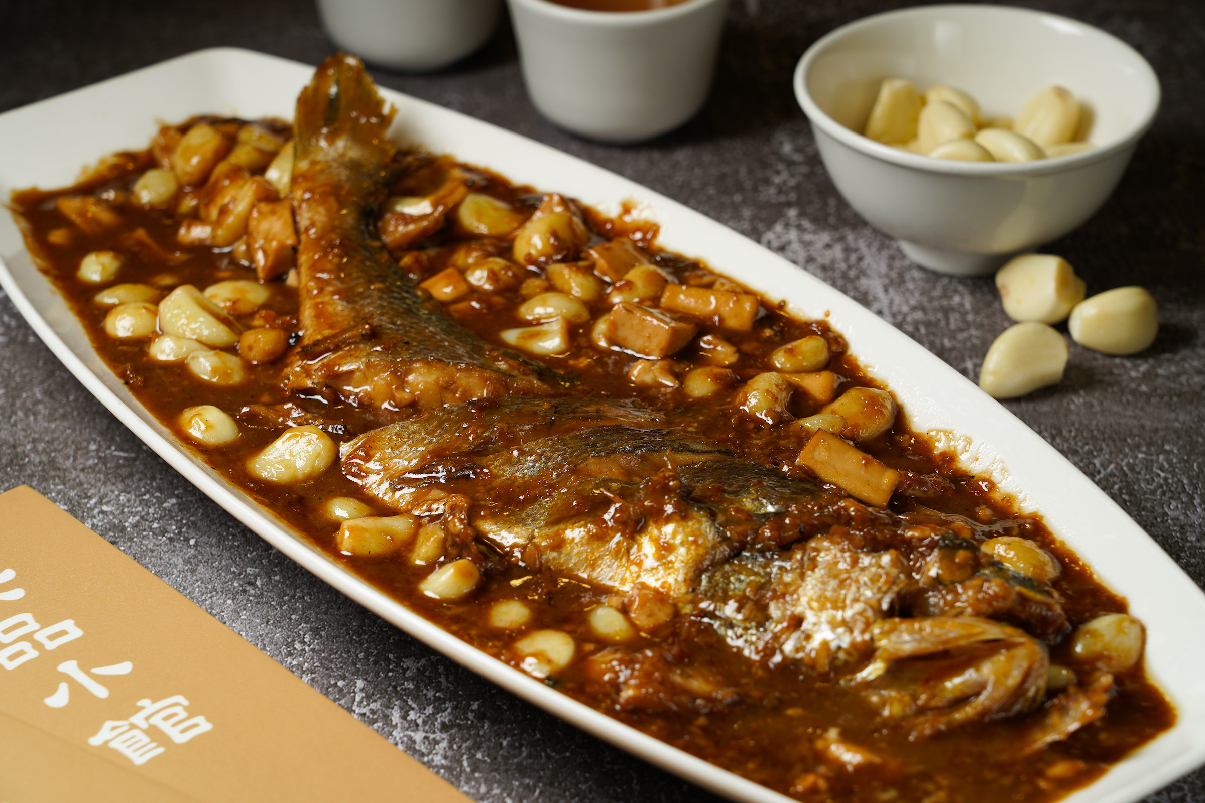 「鮮魚燒豆腐」酒香濃郁，蒜頭燒到沙潤如蜜，豆腐更吸飽了魚的精華。（時價，圖中為1,100元／隻，需1天前預訂）
