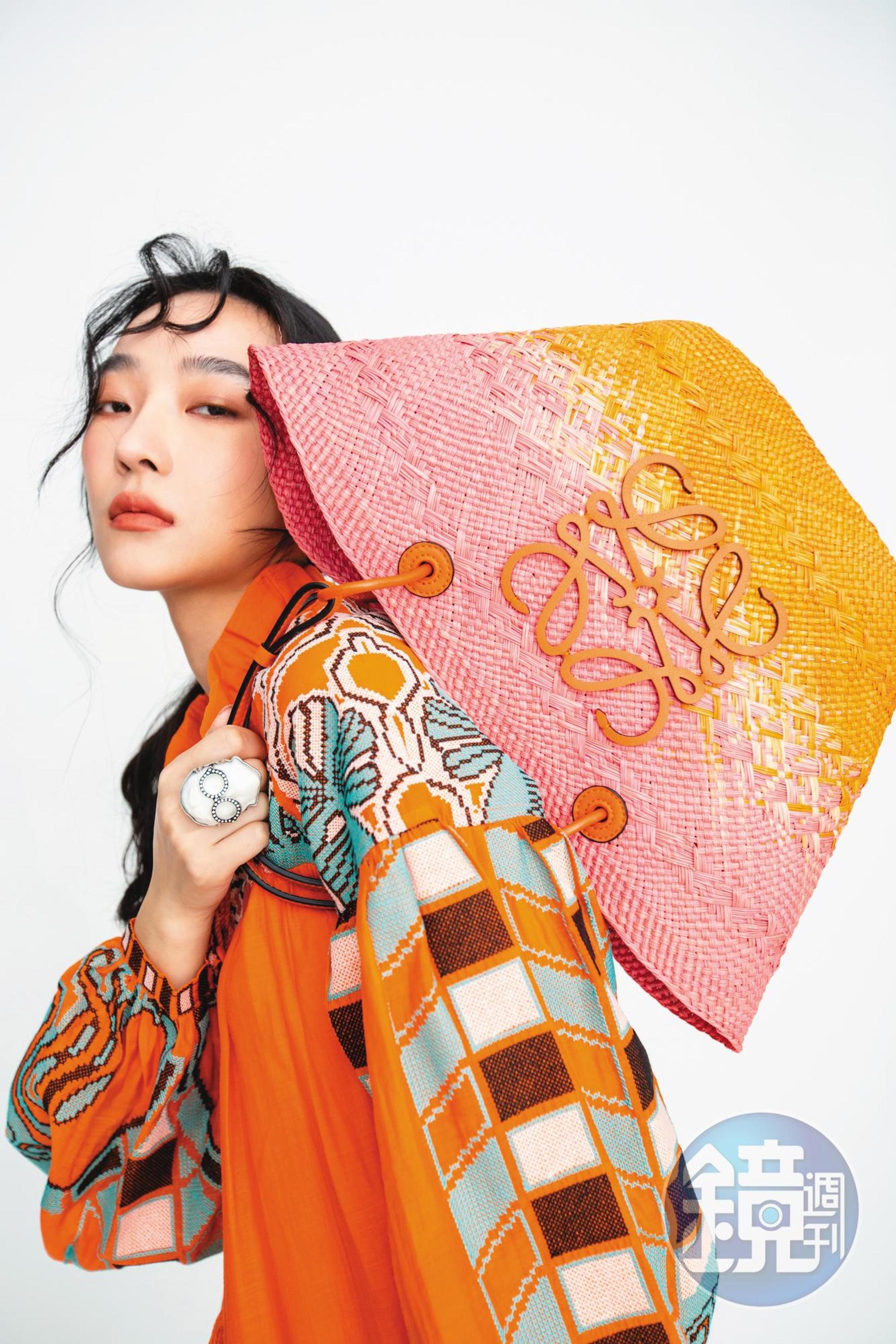 Anagram粉橘漸層色棕櫚葉肩背提籃包 NT$31,000 by LOEWE;印花短洋裝 NT$2,999 by Iris Apfel X H&M;人像造型戒指 NT$1,299 by Iris Apfel X H&M