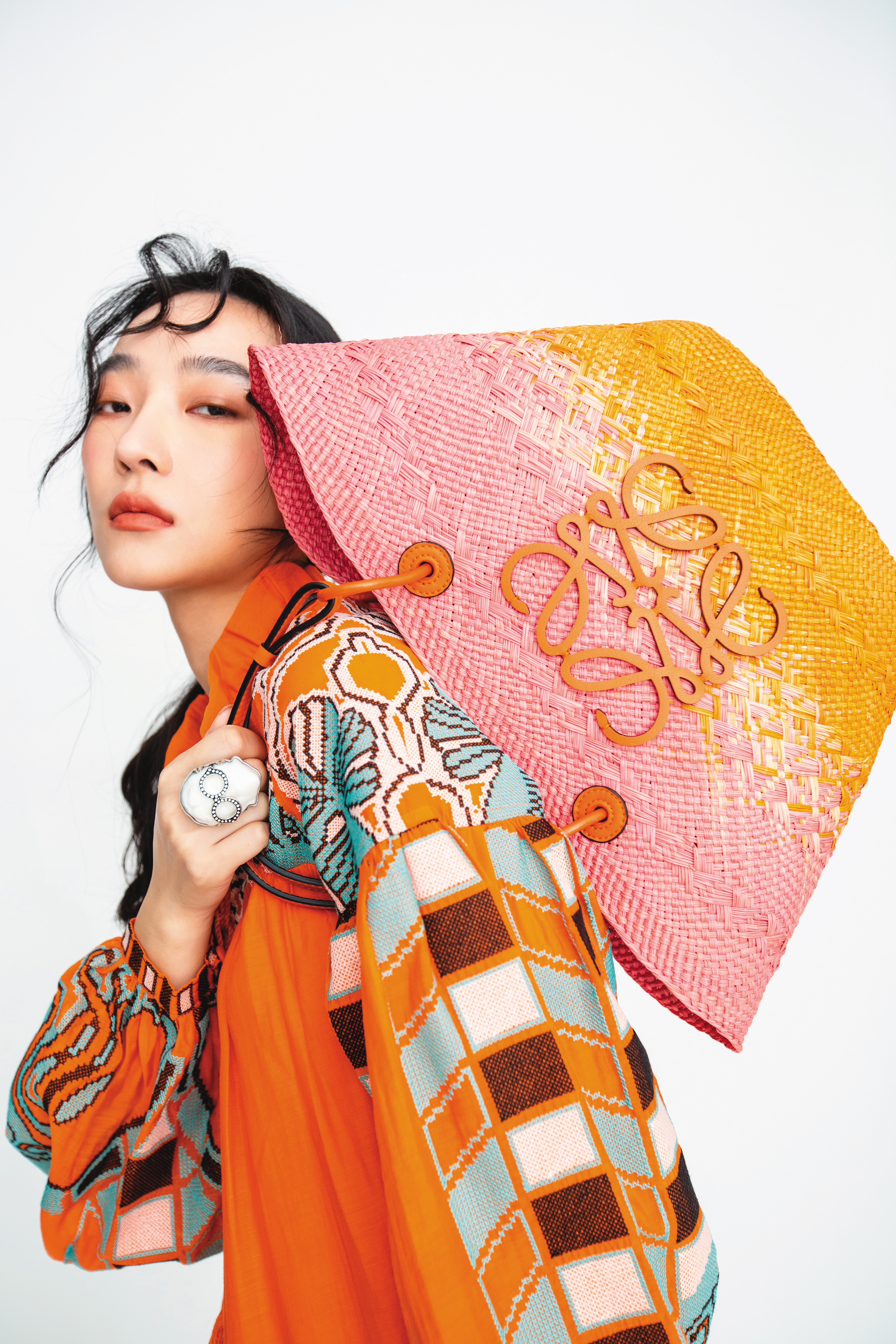 Anagram粉橘漸層色棕櫚葉肩背提籃包 NT$31,000 by LOEWE；印花短洋裝 NT$2,999 by Iris Apfel X H&M；人像造型戒指 NT$1,299 by Iris Apfel X H&M