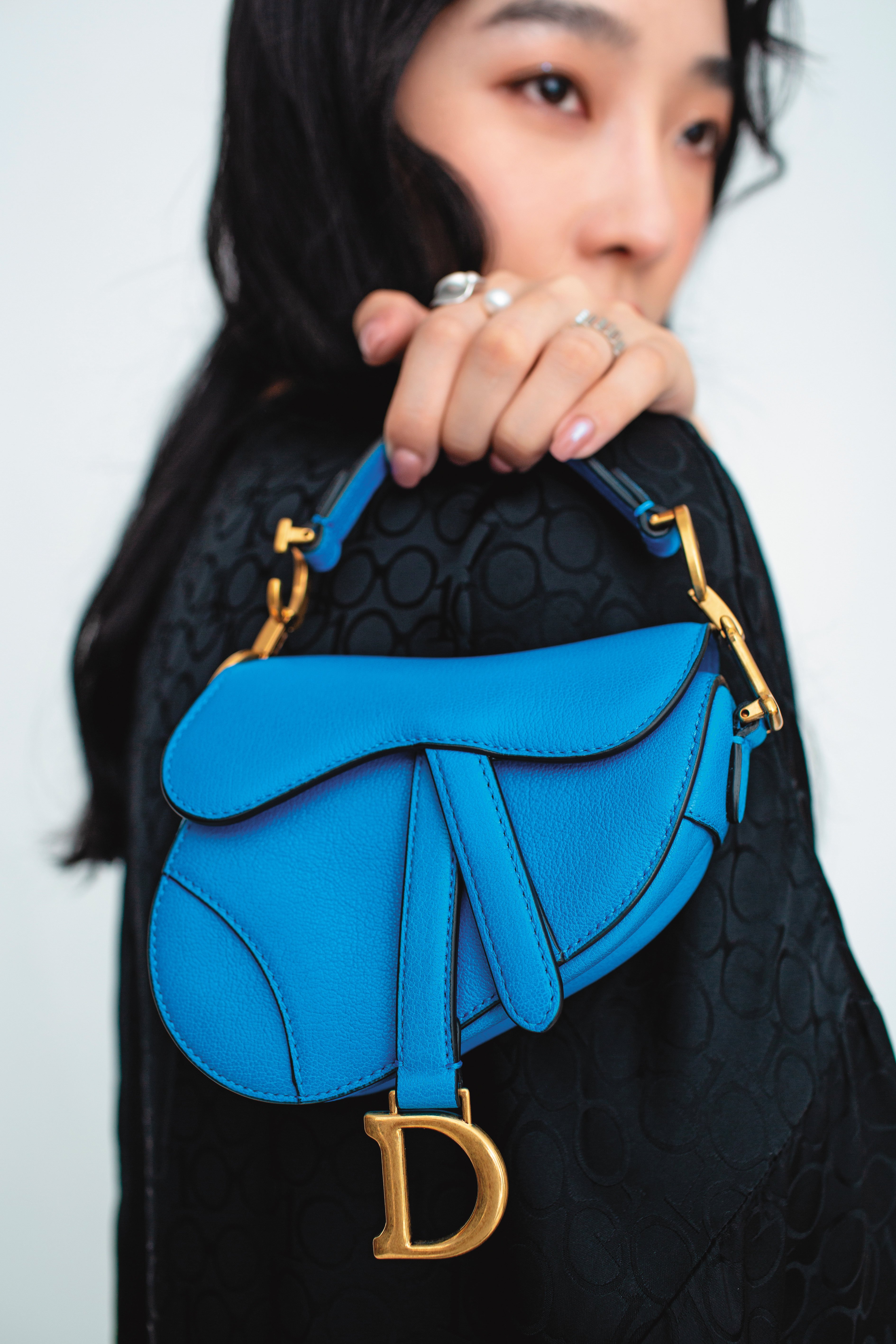 Saddle micro海礁藍山羊皮馬鞍包 NT$79,000 by DIOR；黑色長罩衫 NT$3,499 by Iris Apfel X H&M；可調式淡水珍珠戒指（左） NT$4,980 by OLIVIA YAO JEWELLERY；迴響珍珠寬戒指（右） NT$4,980 by OLIVIA YAO JEWELLERY
