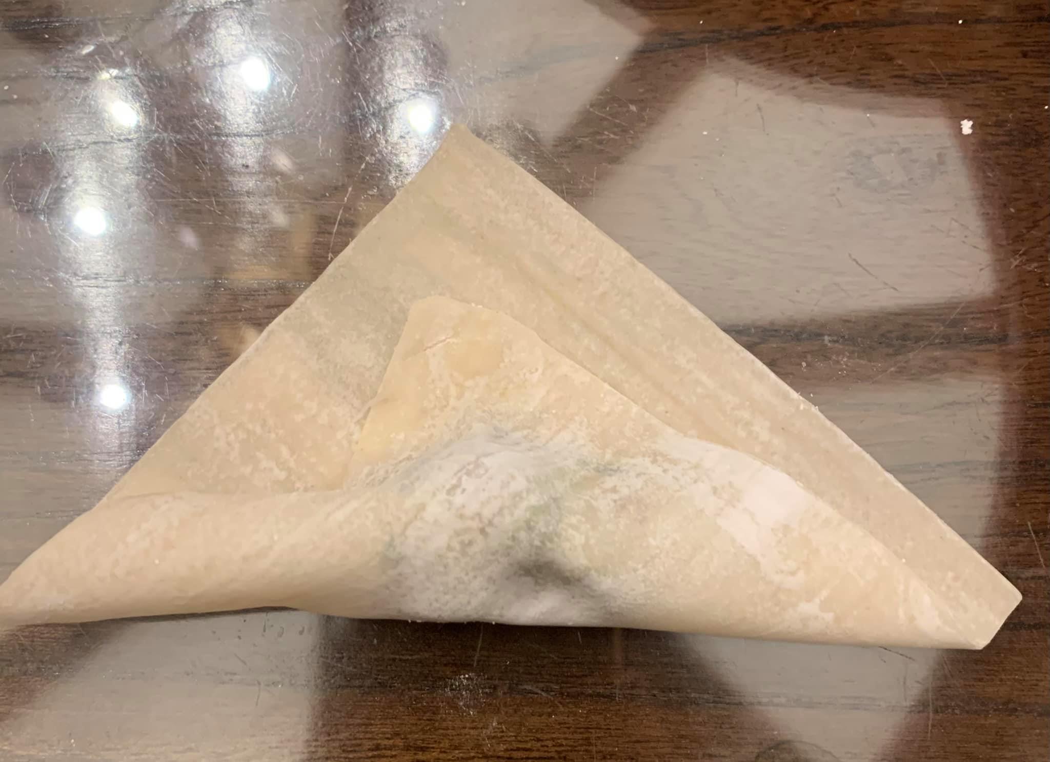 包薺菜餛飩步驟二：一角沾水對折輕壓。