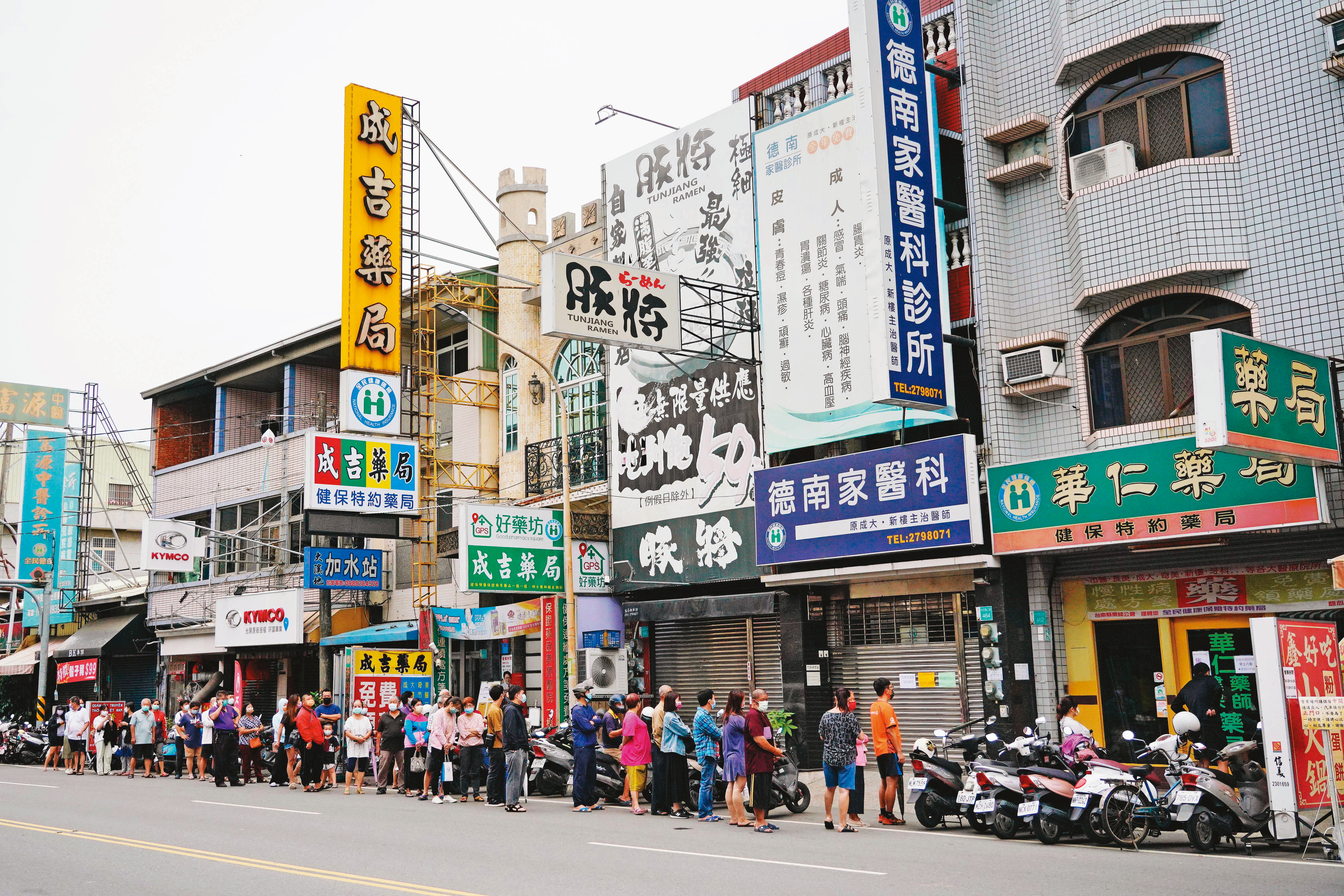 多項防疫措施鬆綁後，快篩劑成為重要防疫工具，搶買實名制快篩的民眾在藥局外大排長龍。