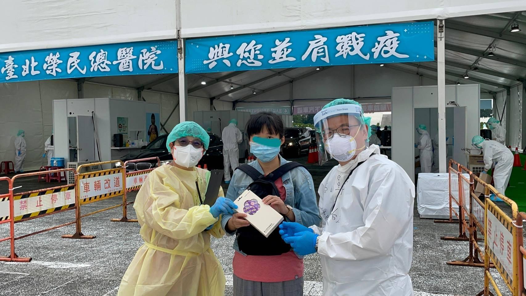 中正紀念堂「車來速」篩檢站啟用至今採檢人數已破萬,場總指揮李偉強副院長、指揮官黃獻皞主任,特別到場致贈北榮紀念口罩一盒給1萬號的民眾作為紀念。(台北榮民總醫院提供)