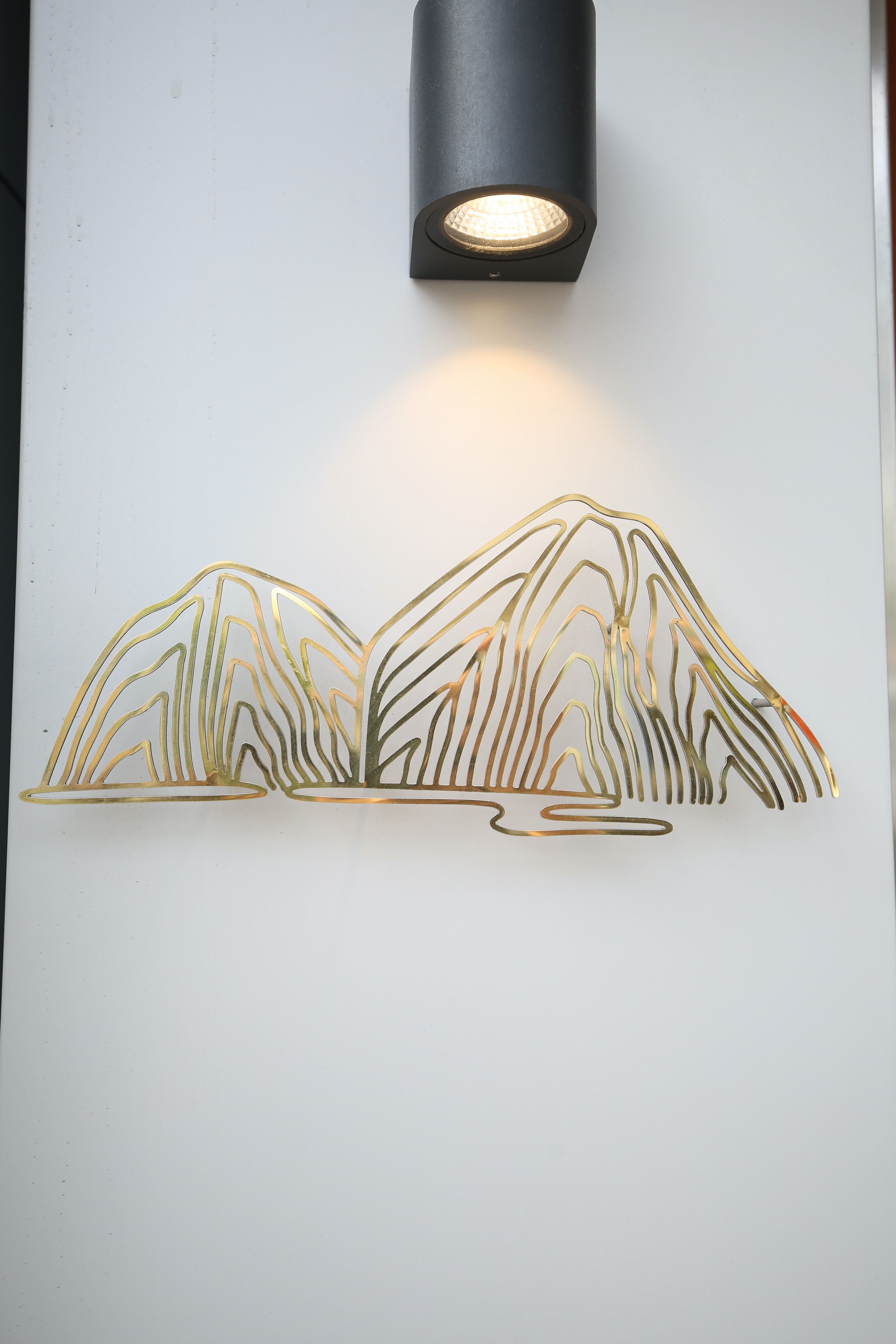 以鍍鈦打造的小籠湯包山谷logo，層疊聳立，帶有禪意。
