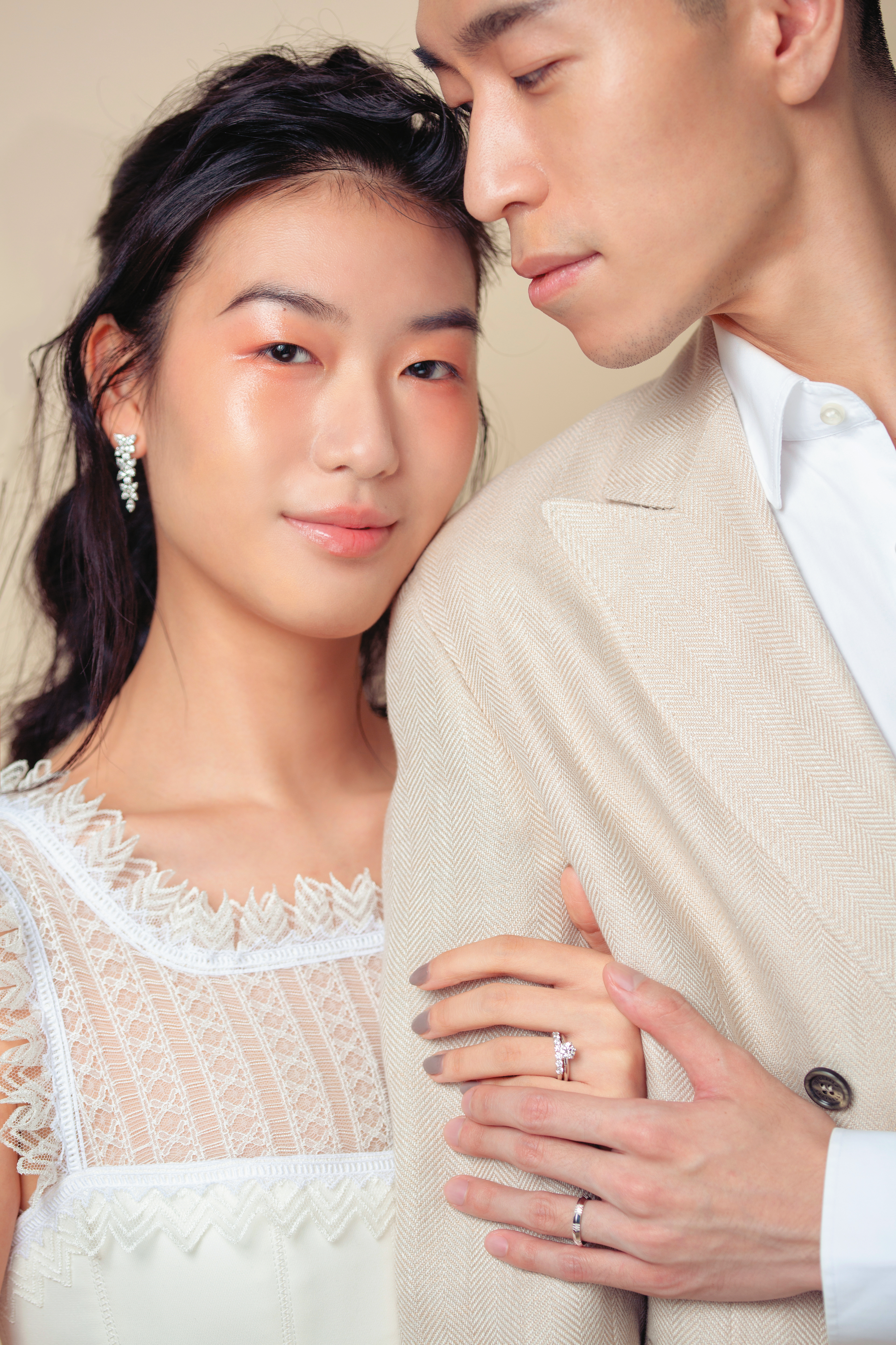 女：（右）The Tiffany Setting經典鉑金六爪鑲嵌鑽戒（總重約1.02克拉），價格店洽，（左）Embrace鉑金鑽戒 NT$200,000；Victoria鉑金鑲嵌混合式切割鑽石耳環 NT$1,555,000 All by TIFFANY；	白色蕾絲上衣 價格店洽 by SHIATZY CHEN。男：Atlas X 18K白金窄版戒指 NT$36,500 by TIFFANY；米色西裝外套 NT$195,400 by Brunello Cucinelli；白色襯衫 價格店洽 by BOSS。