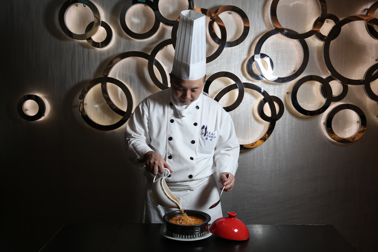 「龍蝦湯泡飯」會推到客人桌邊上菜。圖為品牌長羅嶸在客人桌邊，把炸香米倒入龍蝦湯裡，上菜儀式帶有表演感。