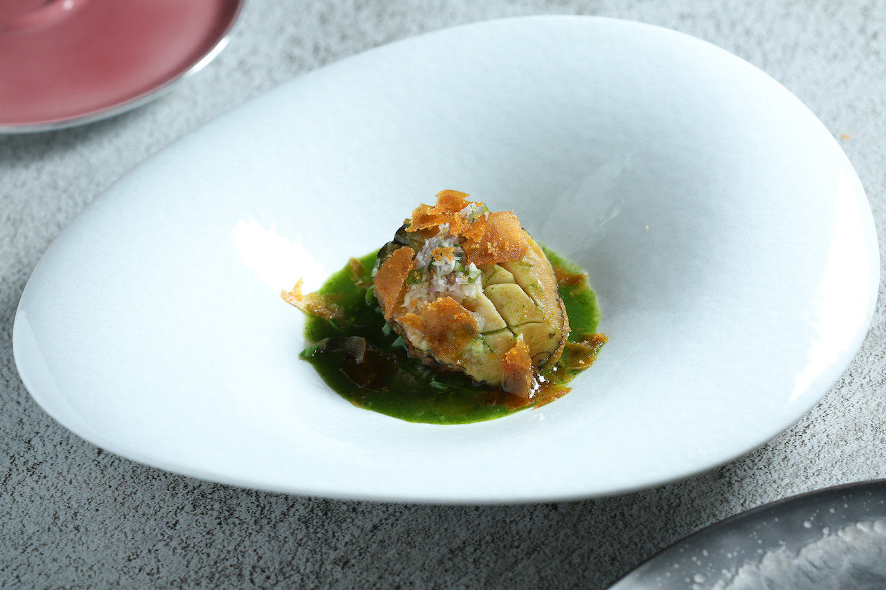 「鹽蒸鮑魚 龍鬚菜 大葉」柔軟彈潤，烏魚子為濃縮蔬菜汁增添鮮鹹感。（Ukai-tei鐵板燒，6,800元套餐菜色）
