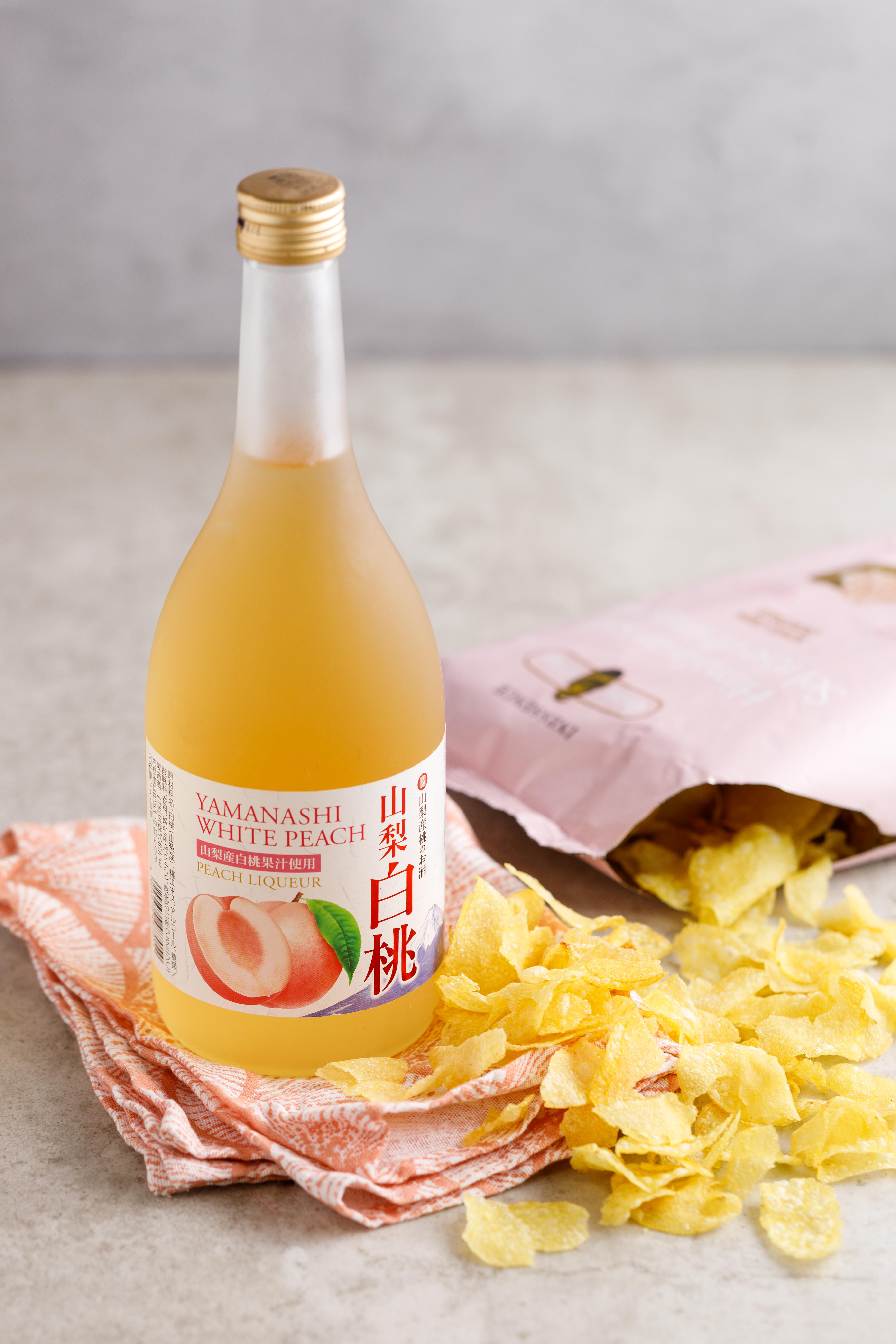 「喜馬拉雅粉紅岩鹽風味洋芋片」（右，119元／包）樸真的鹽味，反而襯托「寶酒造 山梨白桃利口酒」（左，750元／瓶）的甜。