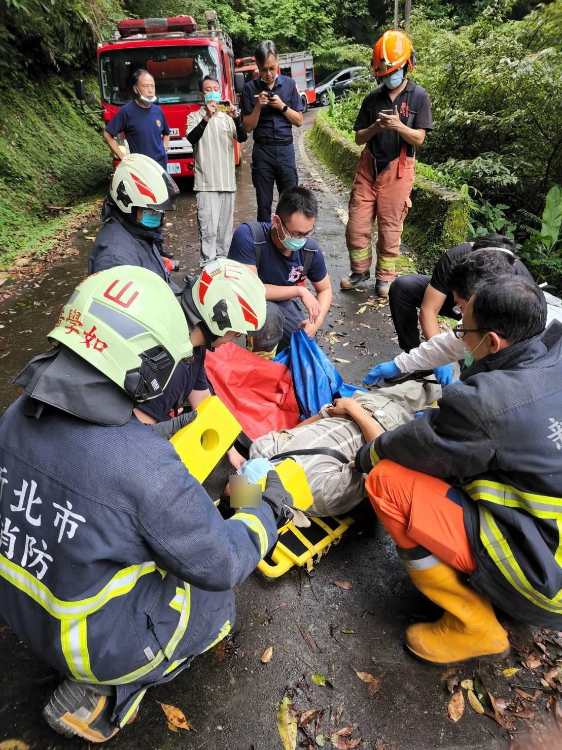 警消將吳姓駕駛(地面上)送往萬芳醫院急救。(新北市消防局提供)