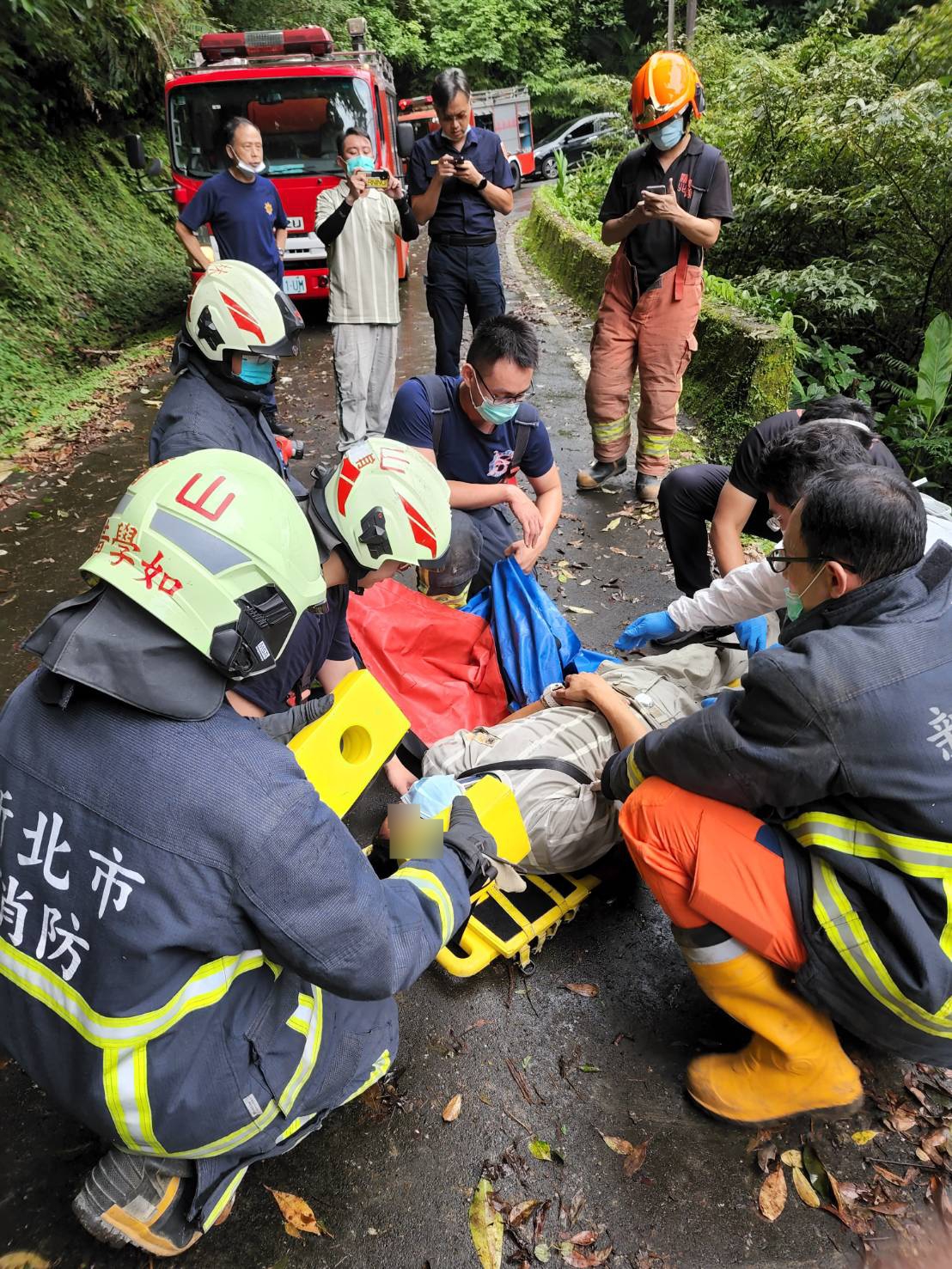 警消將吳姓駕駛(地面上)送往萬芳醫院急救。（新北市消防局提供）