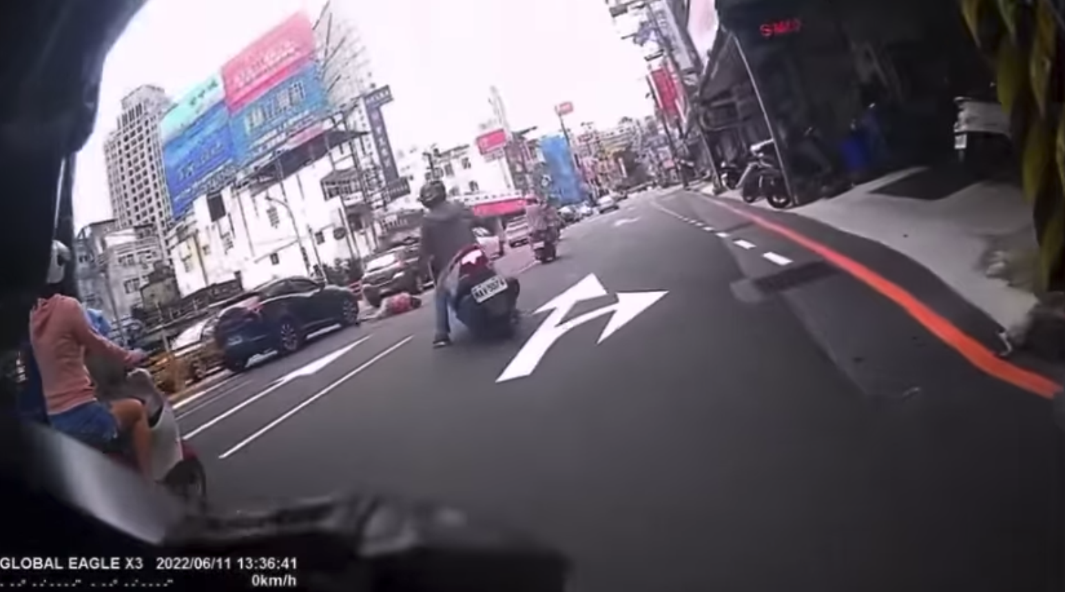 後座婦人跌落路中,後方白色機車騎士上前擋在婦人後方,以防二次車禍。(翻攝爆料公社二社)