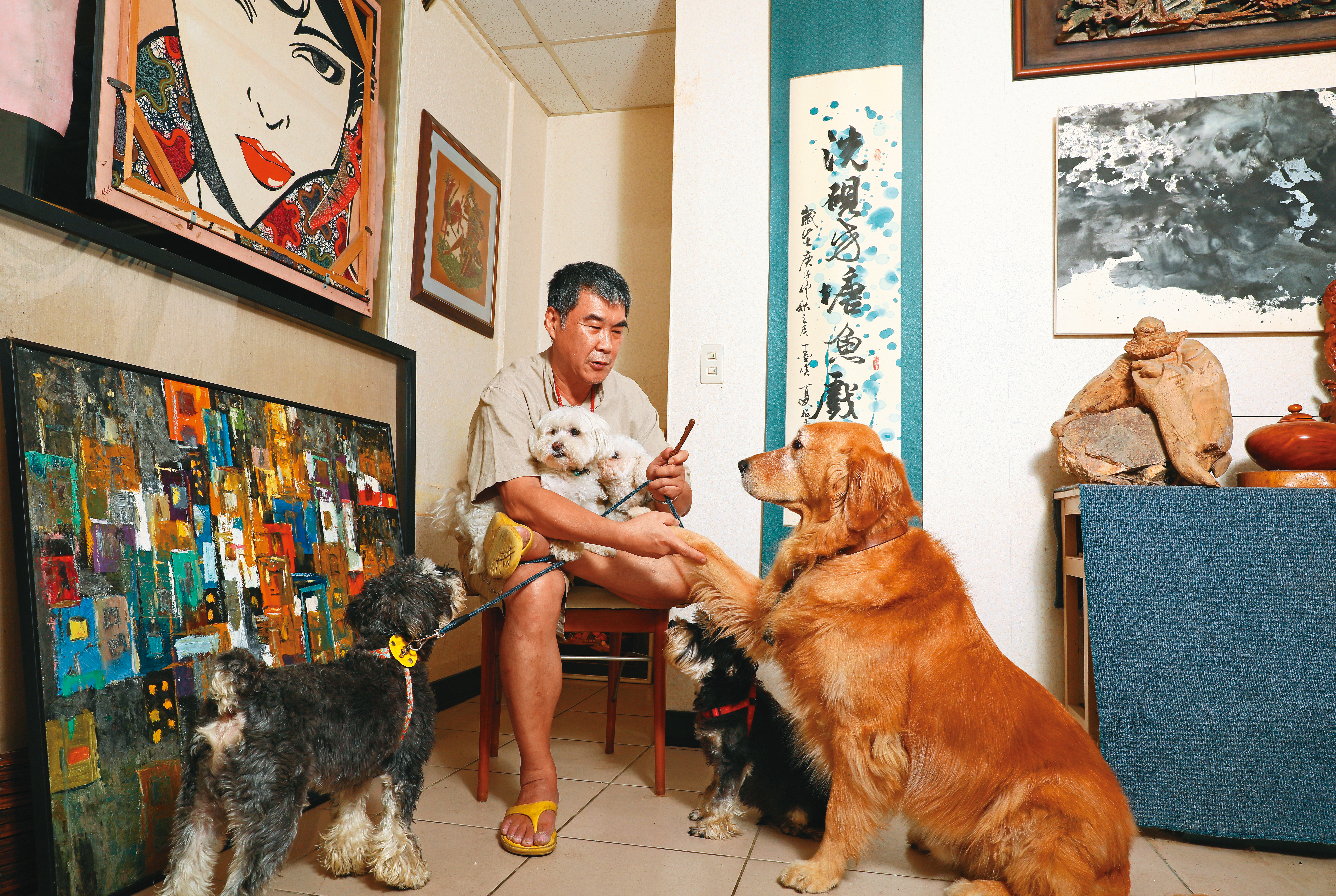 夏紹康與他收養的小狗們。除了是動物救援志工，他同時也是書法家，照片裡的畫與字都是他的作品。