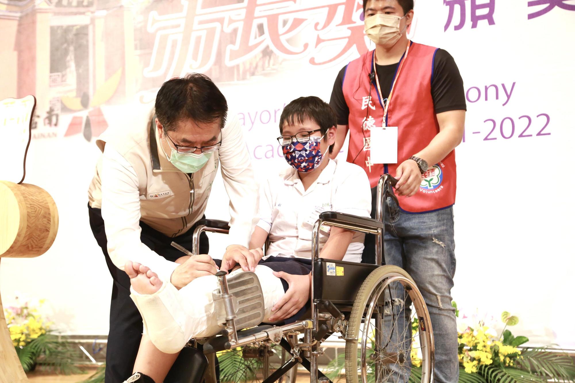 除了開心笑腦，典禮上也是有一些溫馨時刻，市長在受傷學生腳上的石膏簽字為他留念。（台南市政府提供）