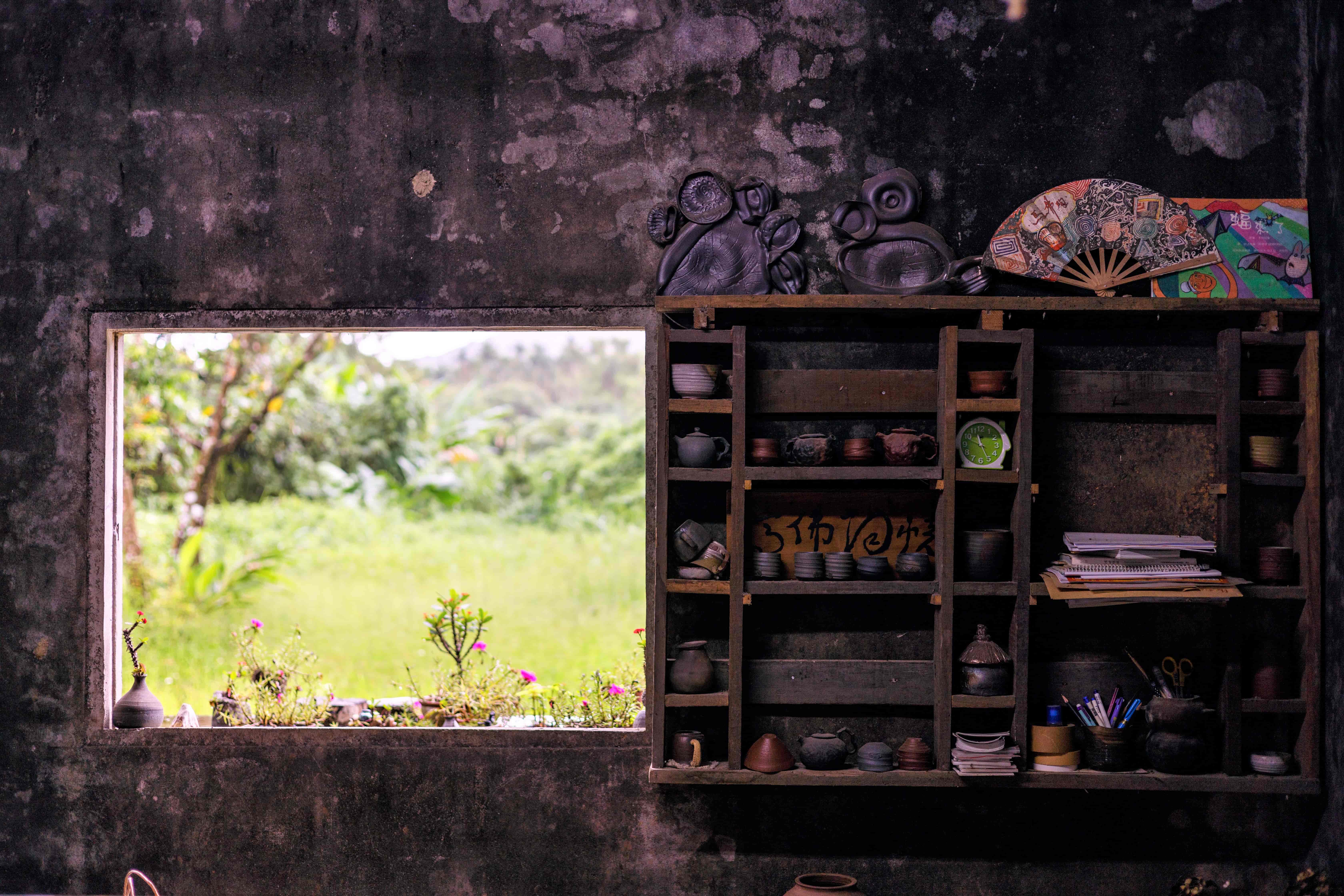 陶燒工作室裡光線低調昏暗，反而讓窗外的明亮俏綠成為一幅畫。