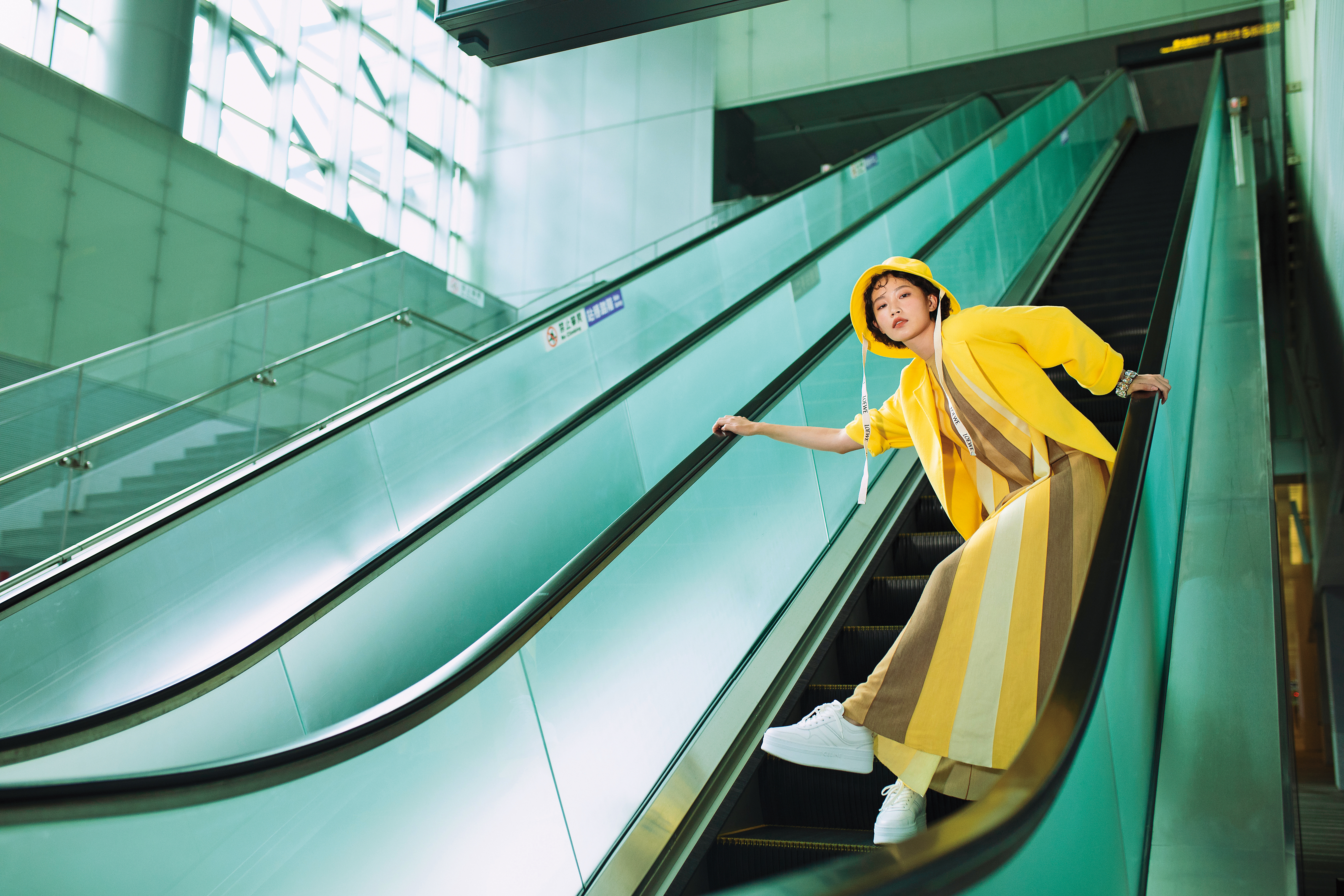 Cashmere與絲質條紋洋裝 NT$109,600 by Loro Piana；Cashmere黃色大衣 NT$214,700 by Loro Piana；厚底皮革運動鞋 NT$27,500 by CELINE；黃色帆布拼小牛皮漁夫帽 NT$17,000 by LOEWE；Harmonia闊手鐲 NT$16,000 by SWAROVSKI。