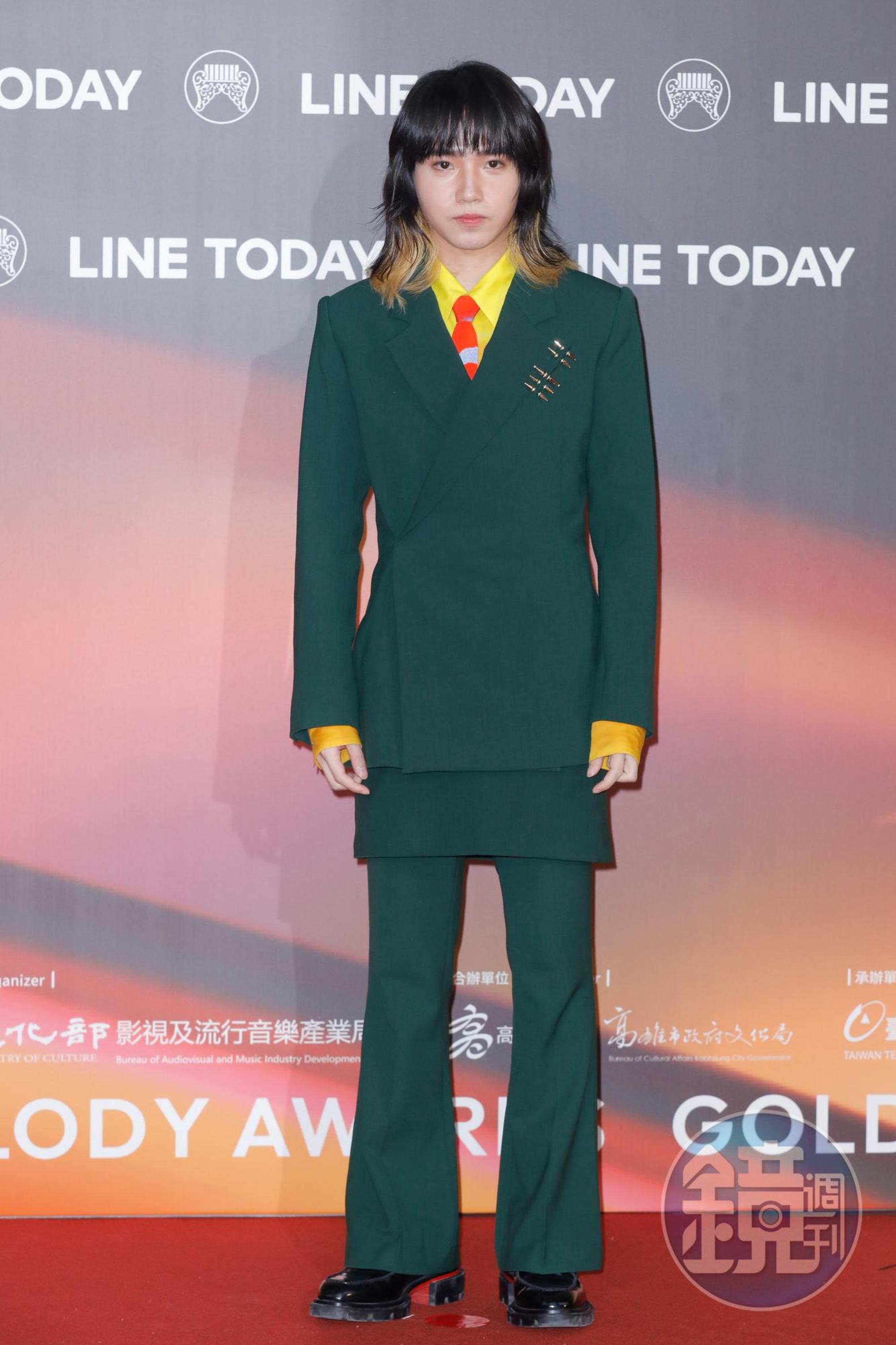 持修身穿全套綠色正裝,搭螢光黃色襯衫及亮橘色領帶紳士中洩露童趣感。