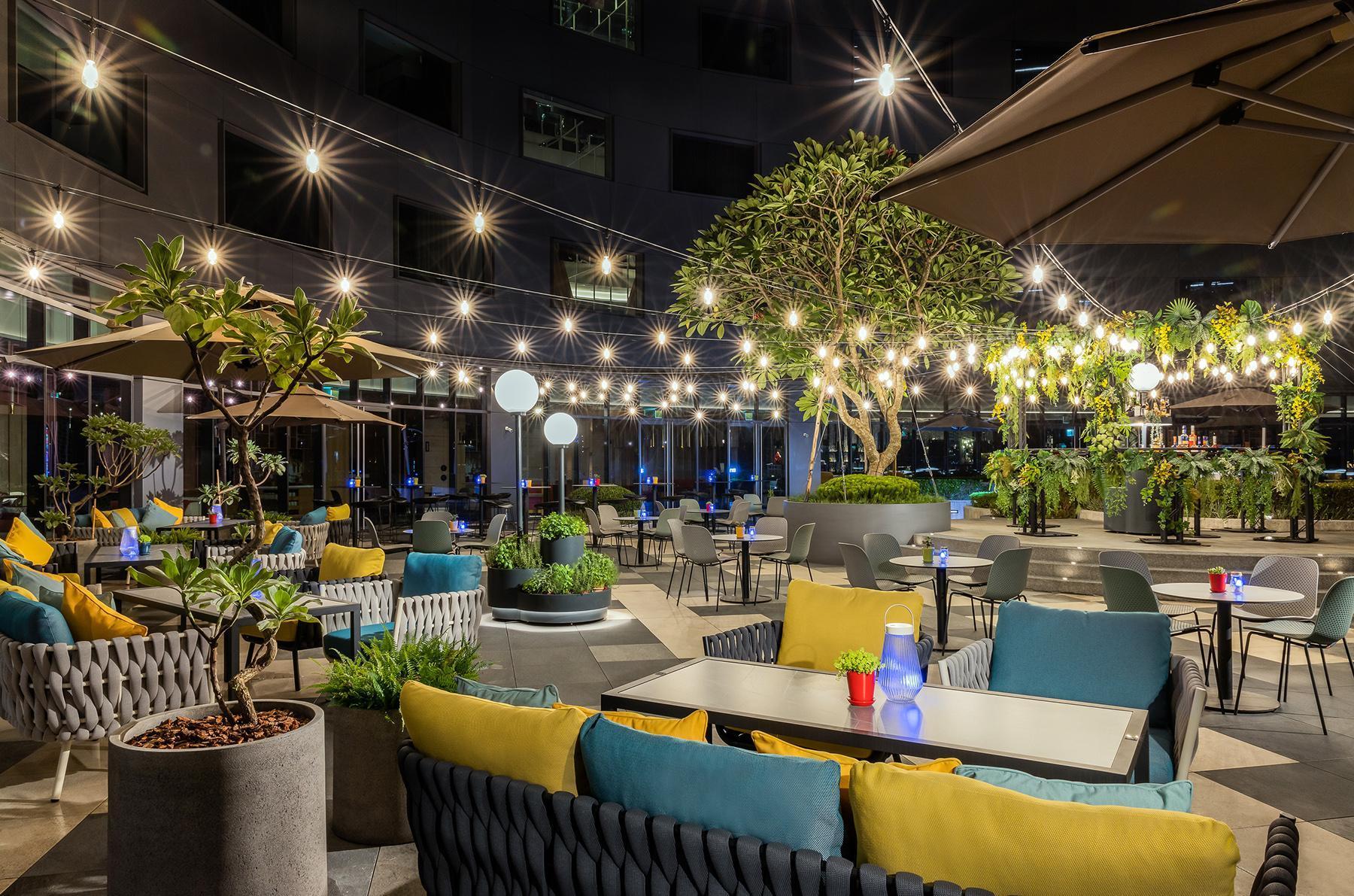 sneaKOut BAR位於酒店4樓戶外空間,周圍充滿綠意的植栽,浪漫串燈、金屬吧台,伴隨輕快音樂體驗,讓人有宛如置身城市綠洲的私密感。(大直英迪格酒店提供)