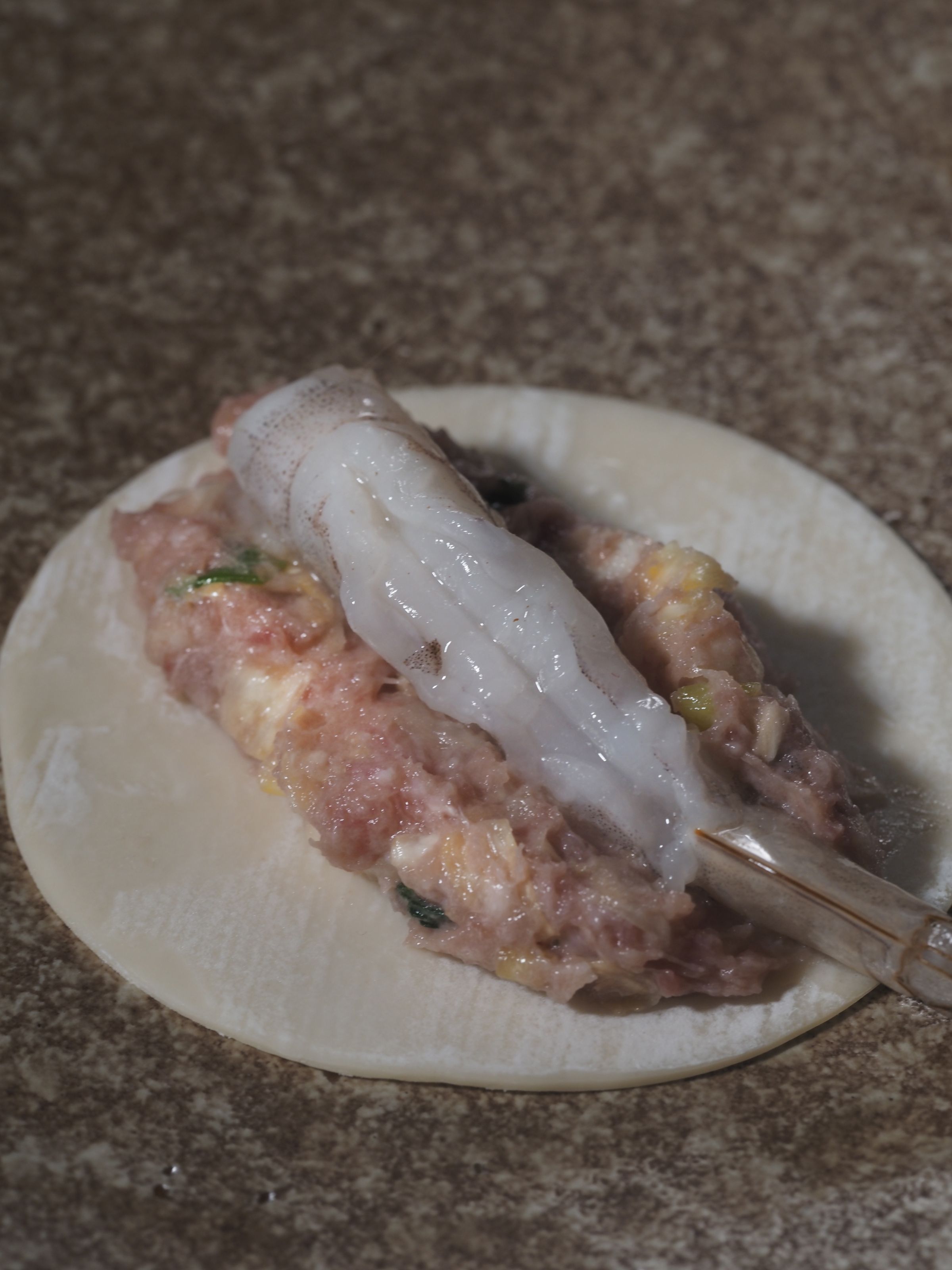 把餡料集中在水餃皮中央再放上蝦子，兩邊留多一點空間比較好包。