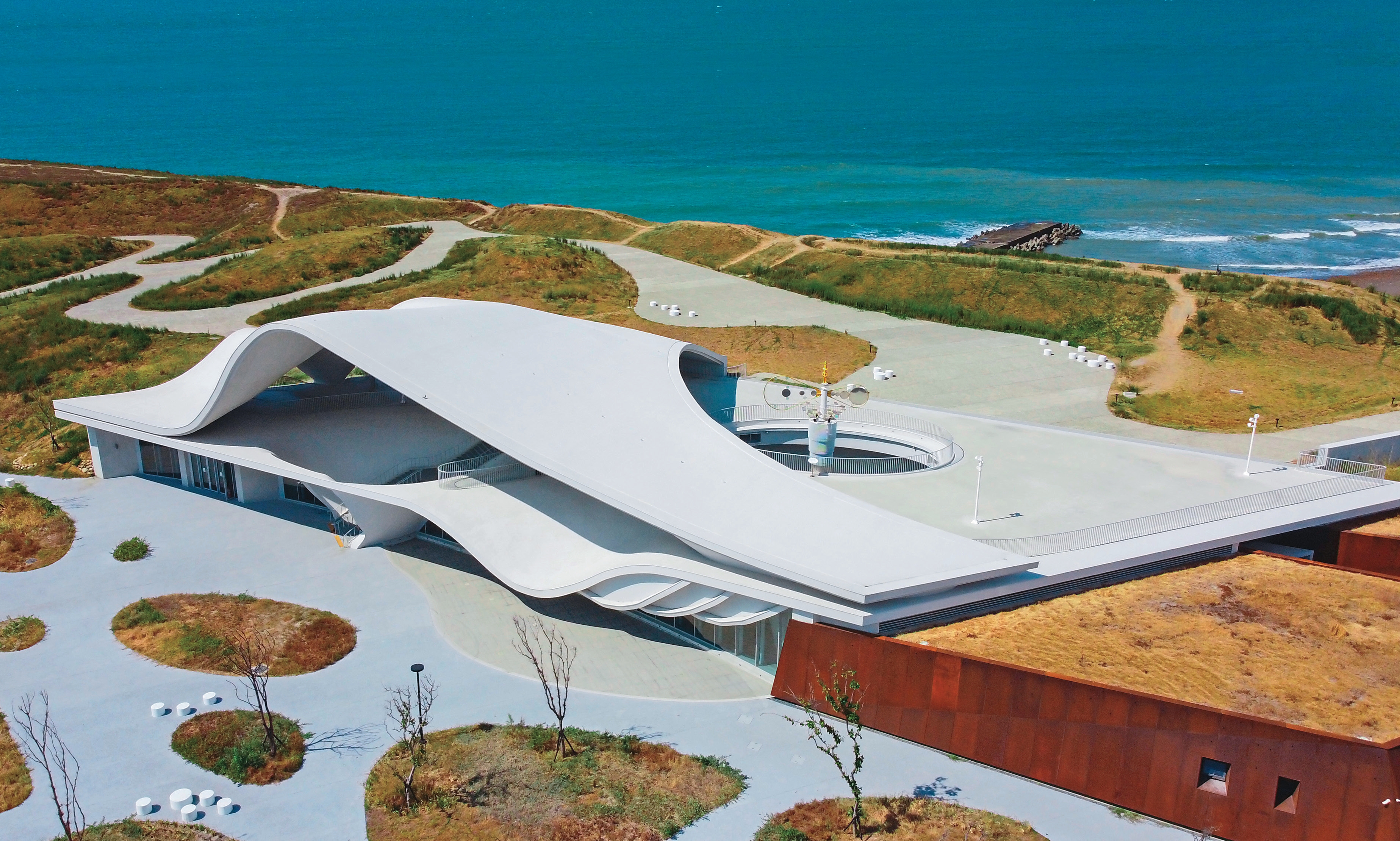 海螺館與外圍象徵石塭的附屬建築，巧妙融入港口與海岸的地景之中。（桃園市政府提供）