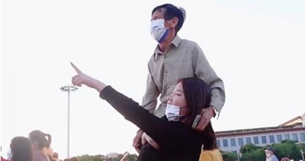 白鴿為了讓父親清楚看到升旗典禮將對方扛在肩上。（翻攝自微博）