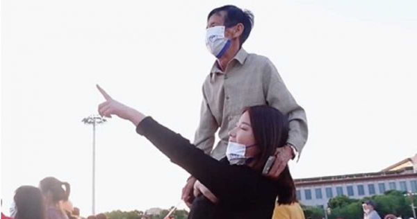 白鴿為了讓父親清楚看到升旗典禮將對方扛在肩上。（翻攝自微博）