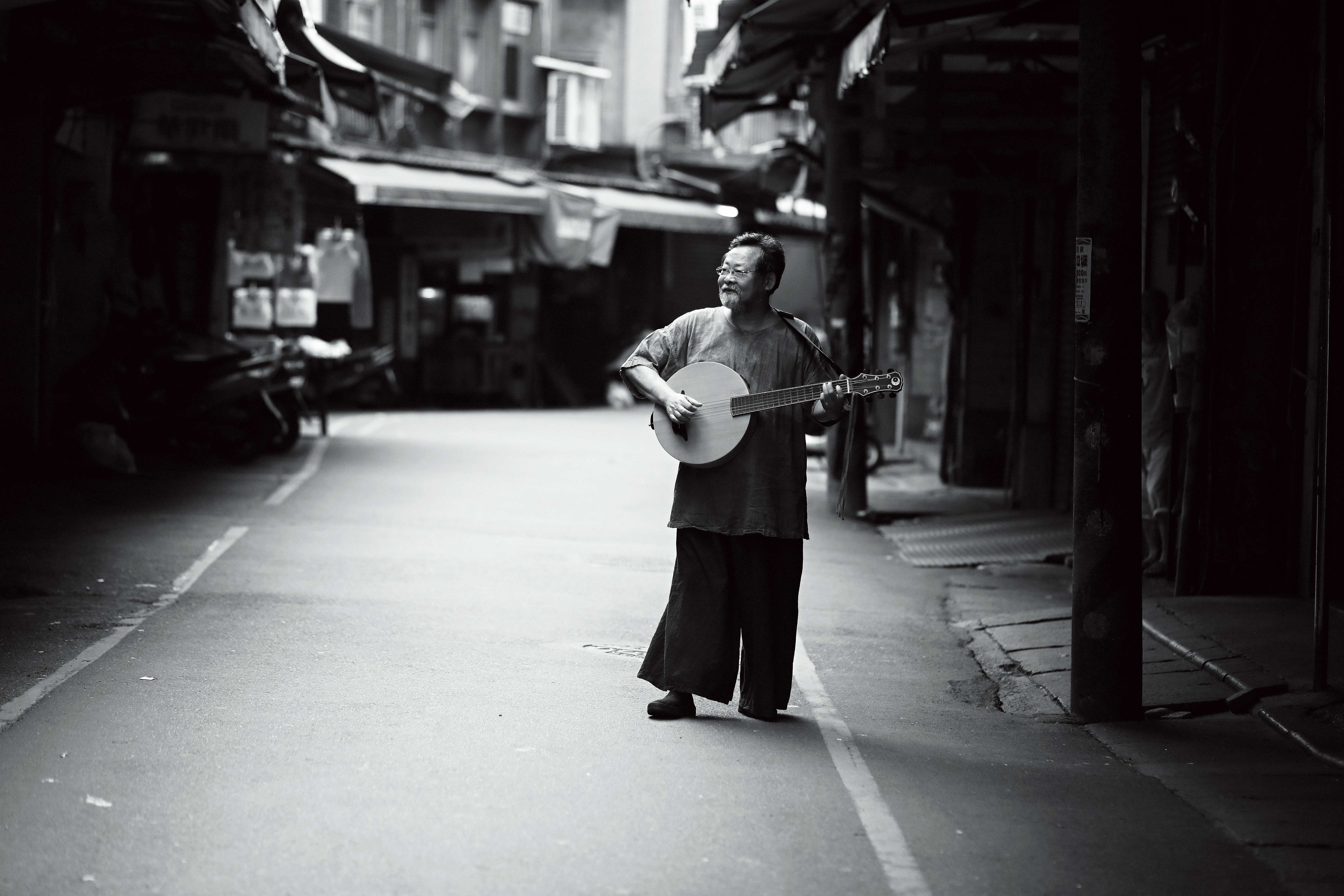 陳明章在北投市場巷弄內。拍攝照片時，他隨手一彈便是《戀戀風塵》配樂的即興演奏。
