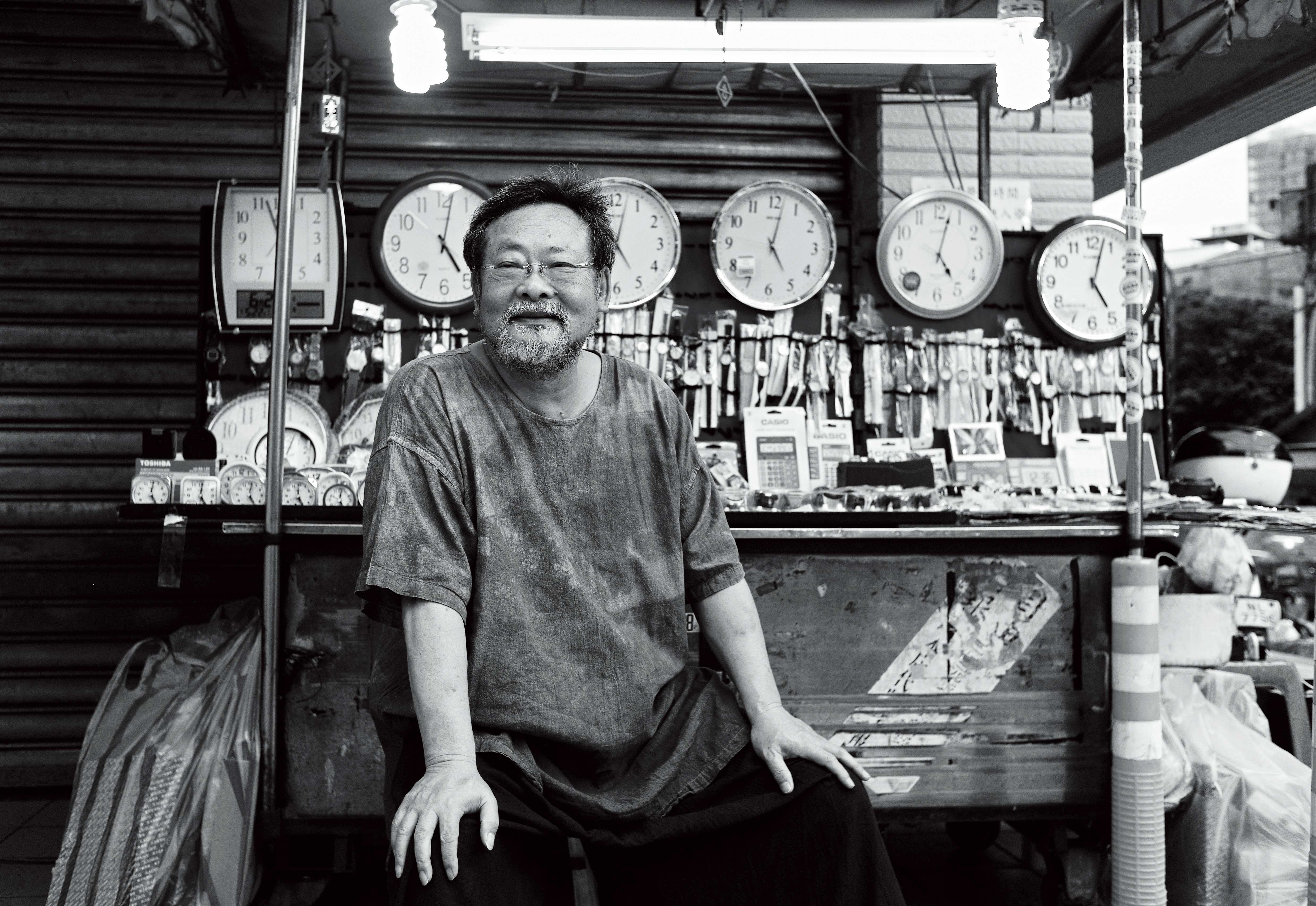 陳明章在北投市場旁的鐘錶攤位拍照。鐘錶攤老闆說自己很久以前就認識陳明章，陳明章的媽媽也常常跟他買鬧鐘。