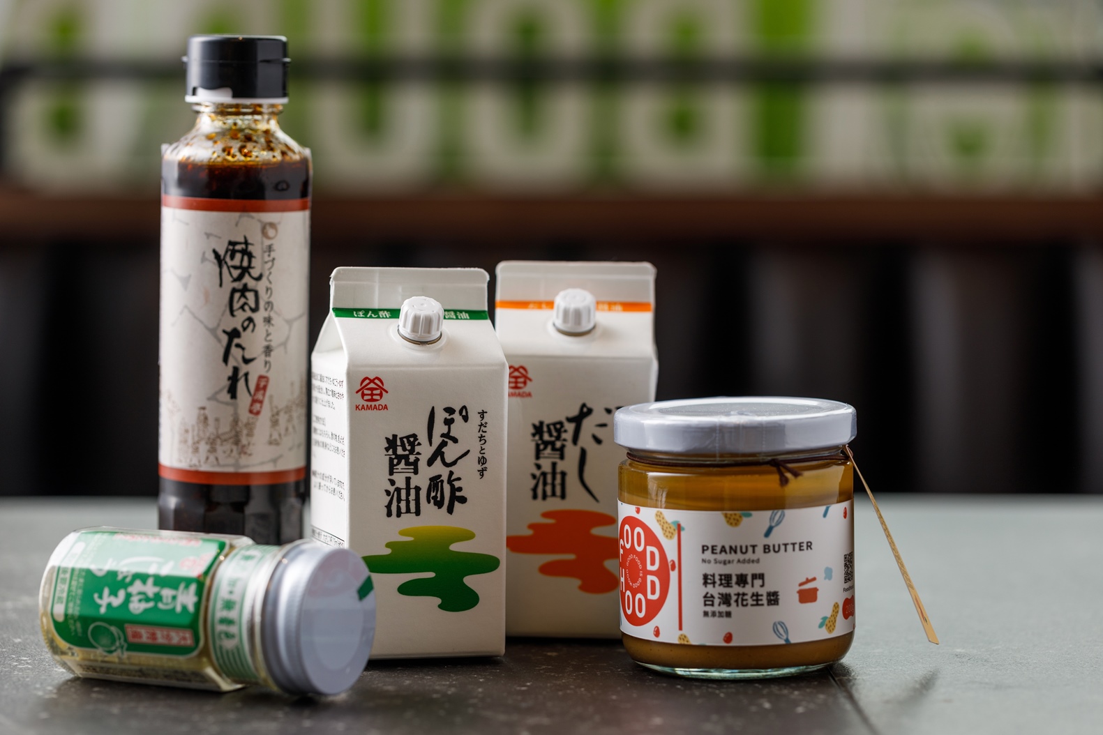 迷你超市販售琳瑯滿目的醬汁與蘸料，推薦「千成亭燒肉醬（左後）」、「鎌田醬油 酸橘醋醬油（左二）」「鎌田醬油 高湯醬油（左三）」、「大分銅金青柚子胡椒（左一）」與苗林行自有品牌「料理專門台灣花生醬（右）」。（價格店洽）