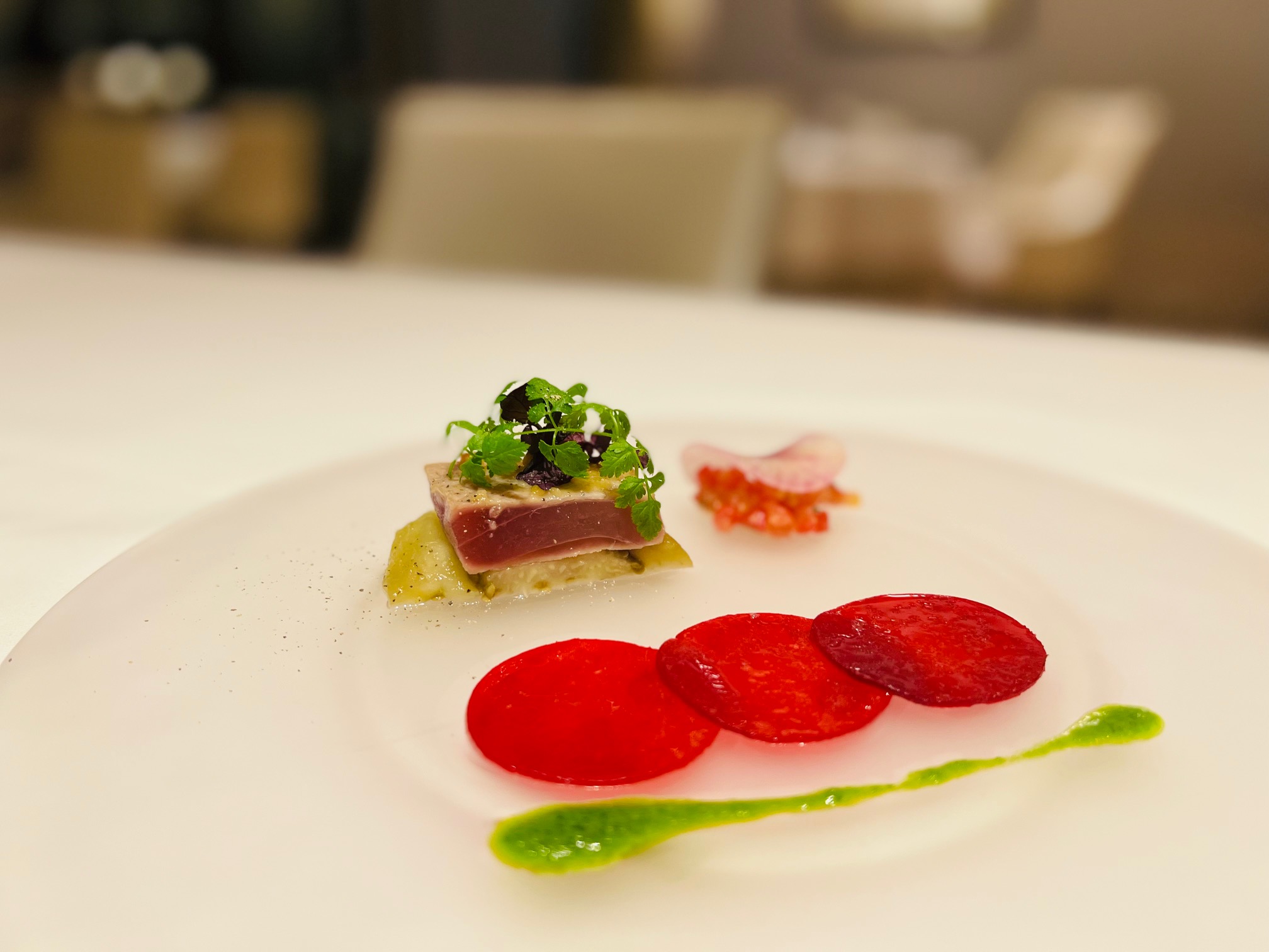 「鮪魚 甜菜根 味噌」甜菜根薄片以深紅、淺紅依序疊放，陪襯著青醬畫盤，多種顏色錯落點綴。