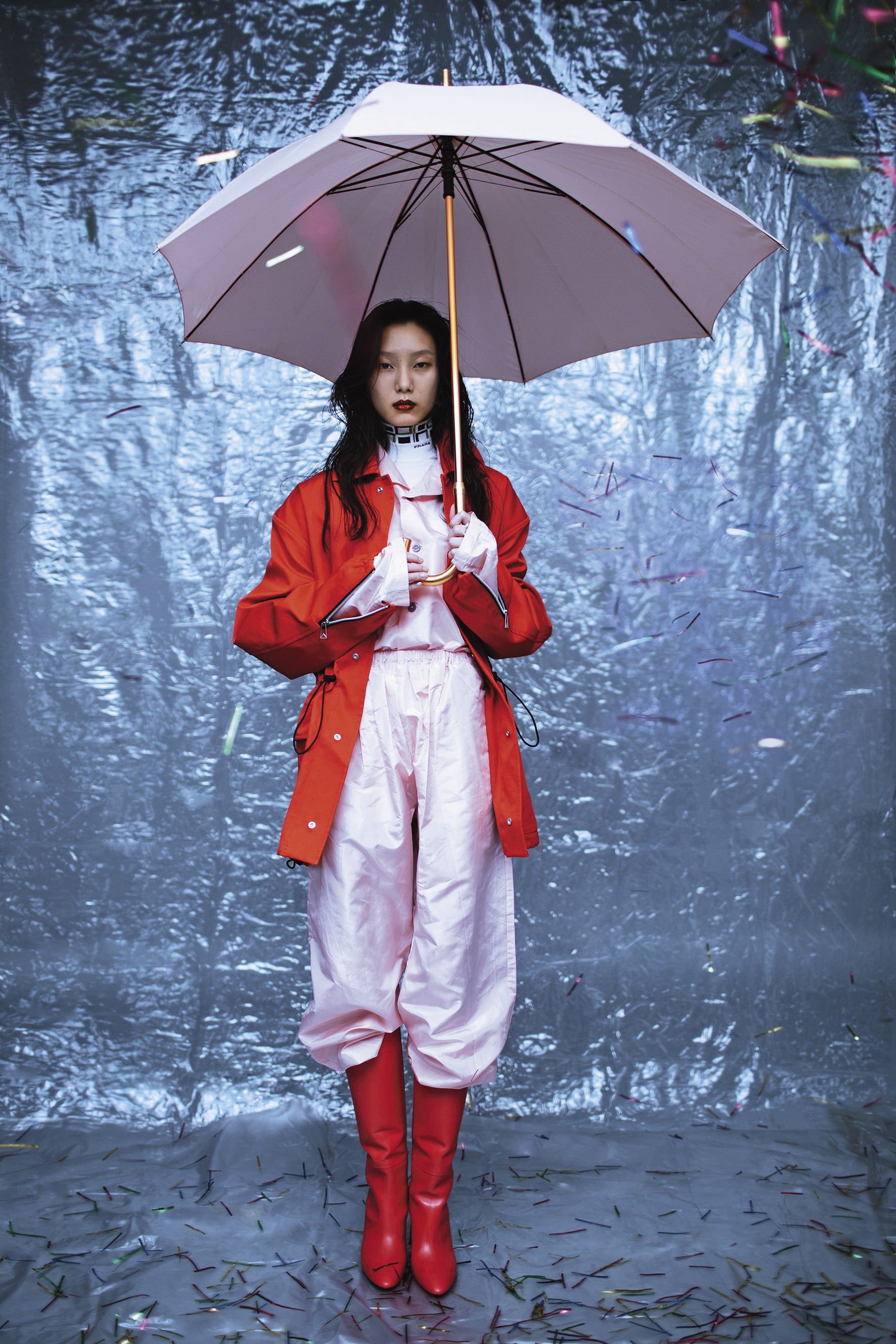 烈紅抽繩外套，價格店洽 by BOTTEGA VENETA；粉紅色印花襯衫 ；價格店洽 by PRADA；粉紅色長褲 ；價格店洽 by PRADA；幾何高領長袖內搭 ，價格店洽 by PRADA；紅色高跟長靴， NT$31,800 by LONGCHAMP。