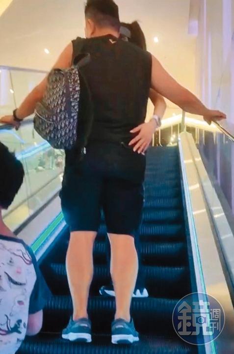 楊麗菁伸手扶上男友的腰，接著就往另一半的翹臀拍上去，把握搭手扶梯的時光調情。（讀者提供）