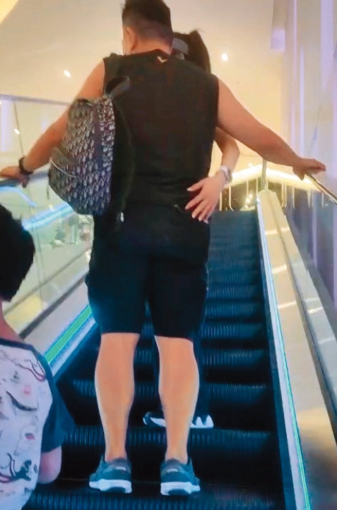 楊麗菁伸手扶上男友的腰，接著就往另一半的翹臀拍上去，把握搭手扶梯的時光調情。（讀者提供）