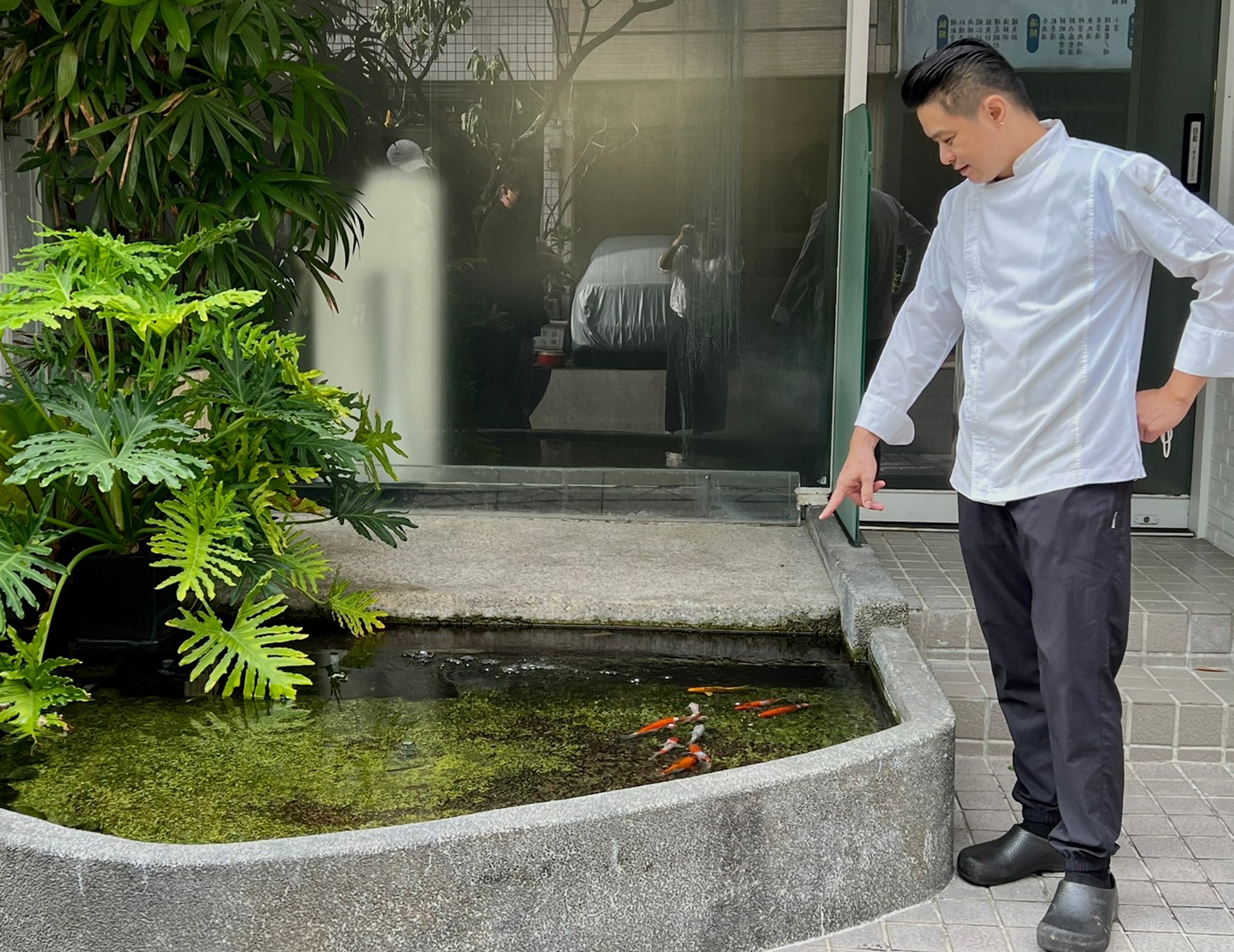 主廚楊彥希與他的庭院裡的魚及植物。