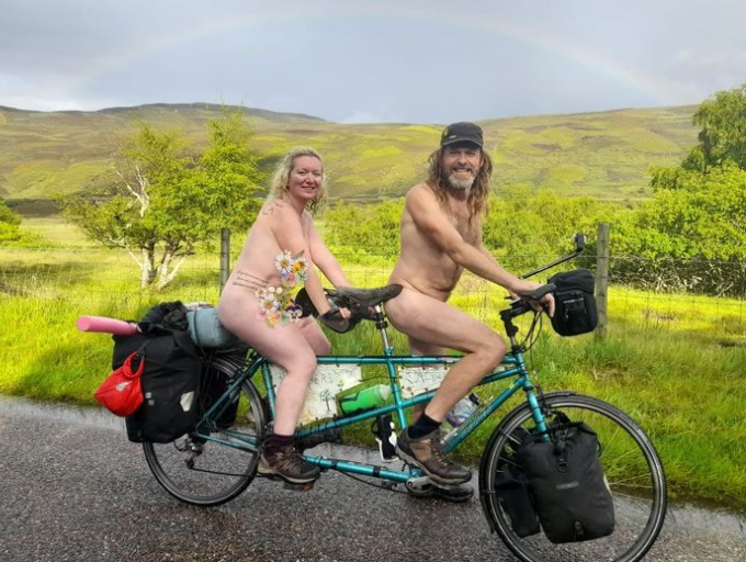 英國女子薩迪（後）和男友柯林（前）都是自然主義者，日前他們脫光光騎腳踏車參加活動。（翻攝每日快報）